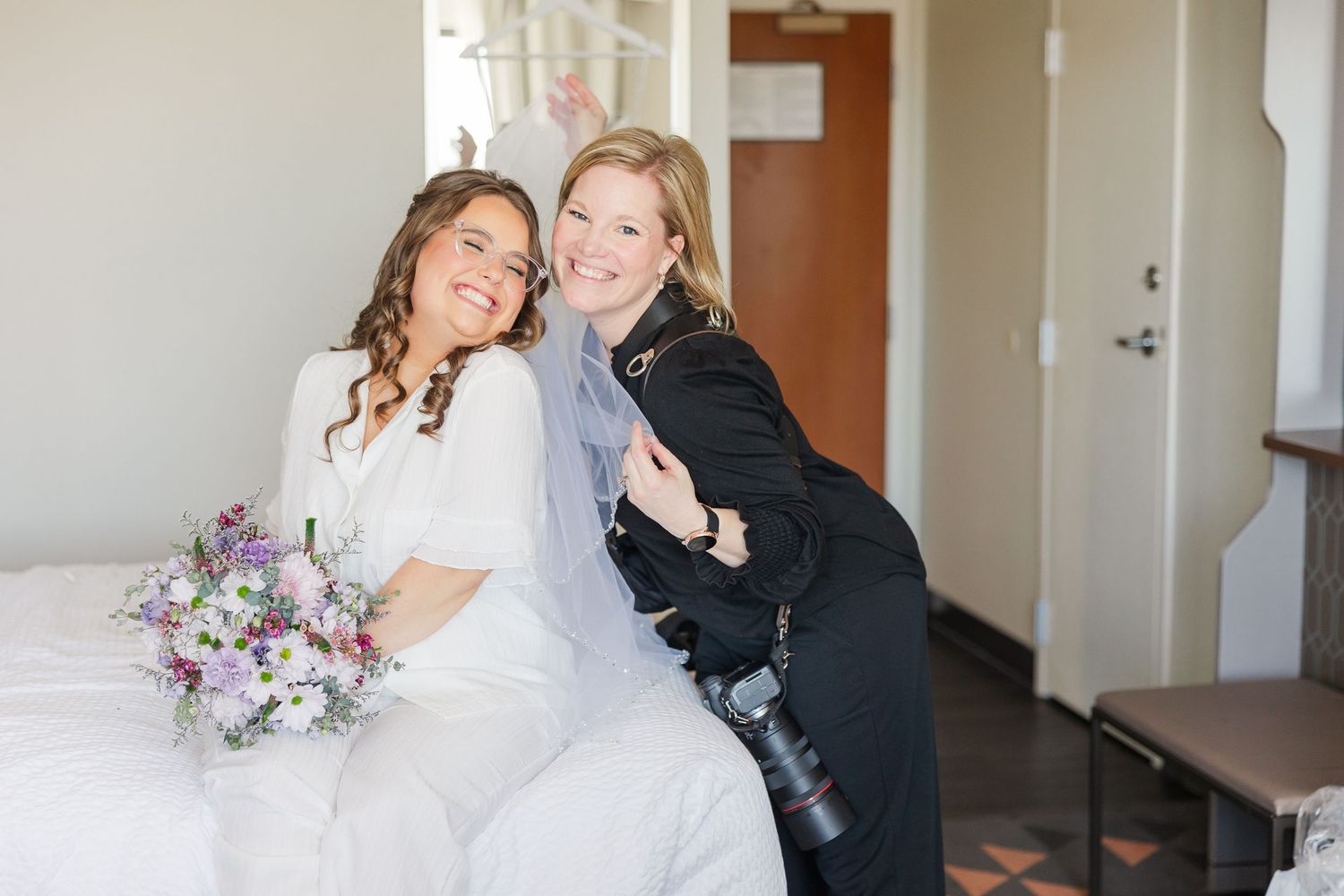 Cassie Lacina smiling with a bride during wedding morning preparations