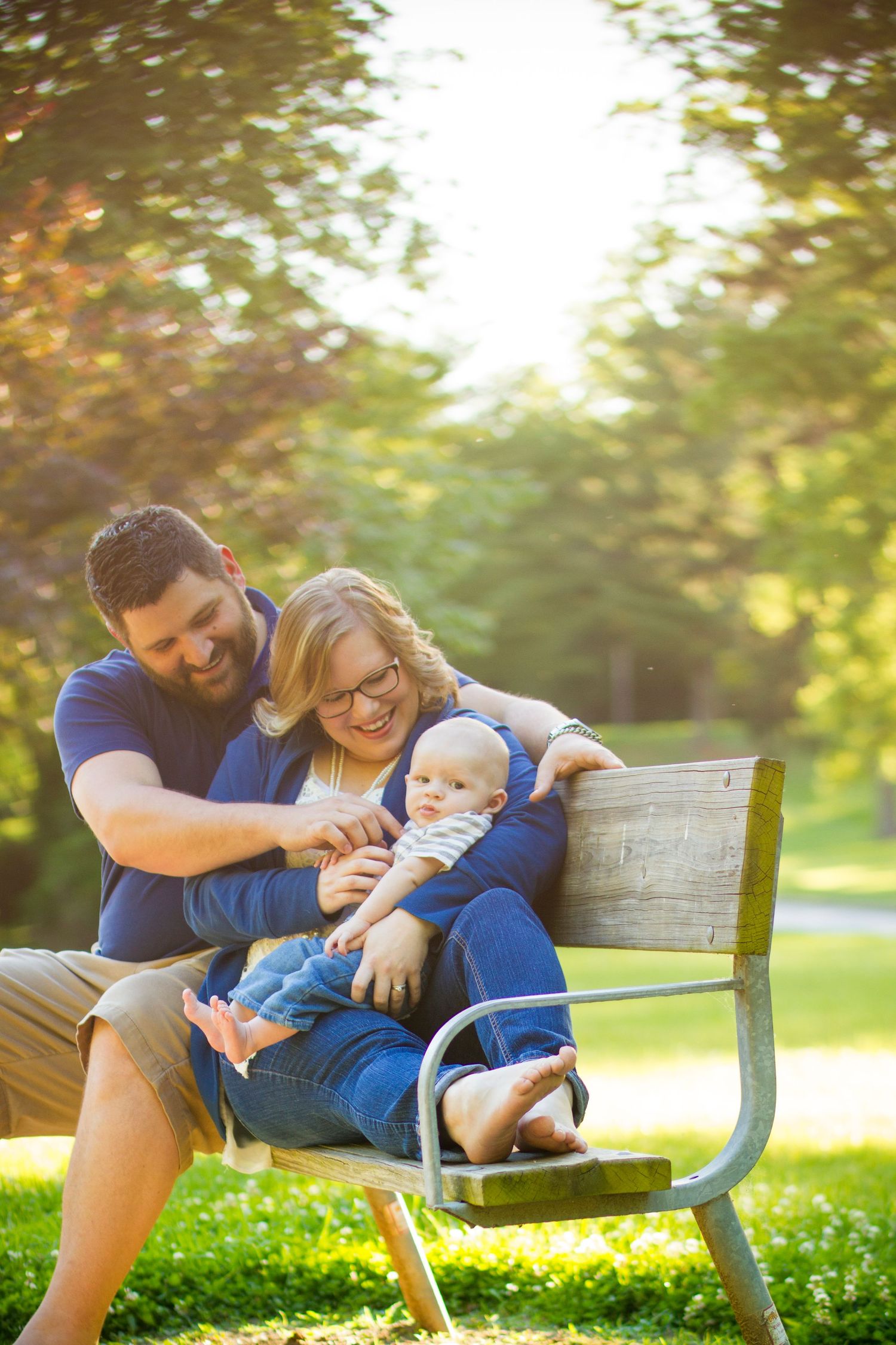 Family relaxing together on a park bench during golden hour.