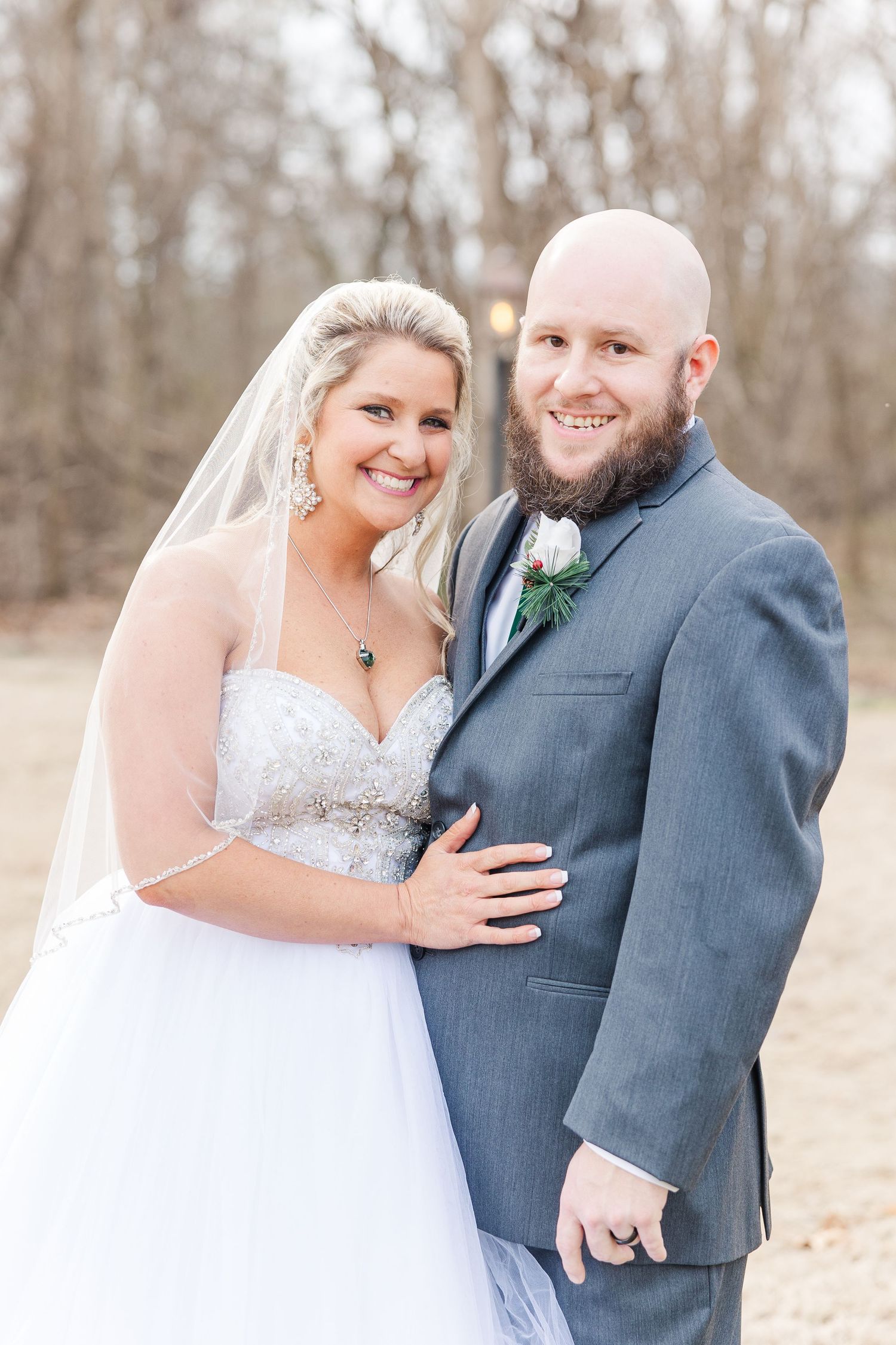 Newlyweds share an intimate moment in their wedding attire against a natural wooded background.