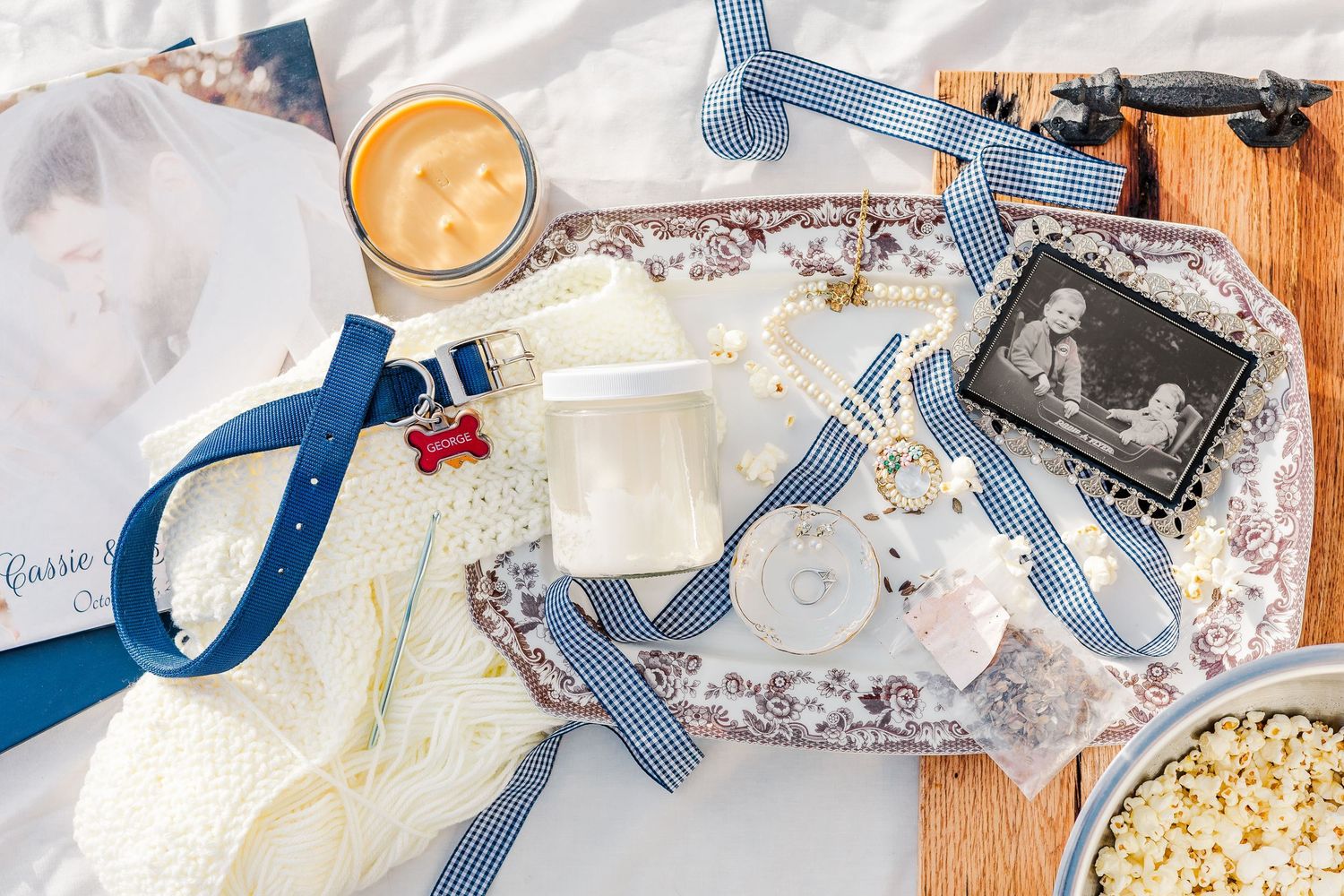A flat lay of holiday gift wrapping supplies including ribbon, scissors, tape, and paper on a wooden surface.