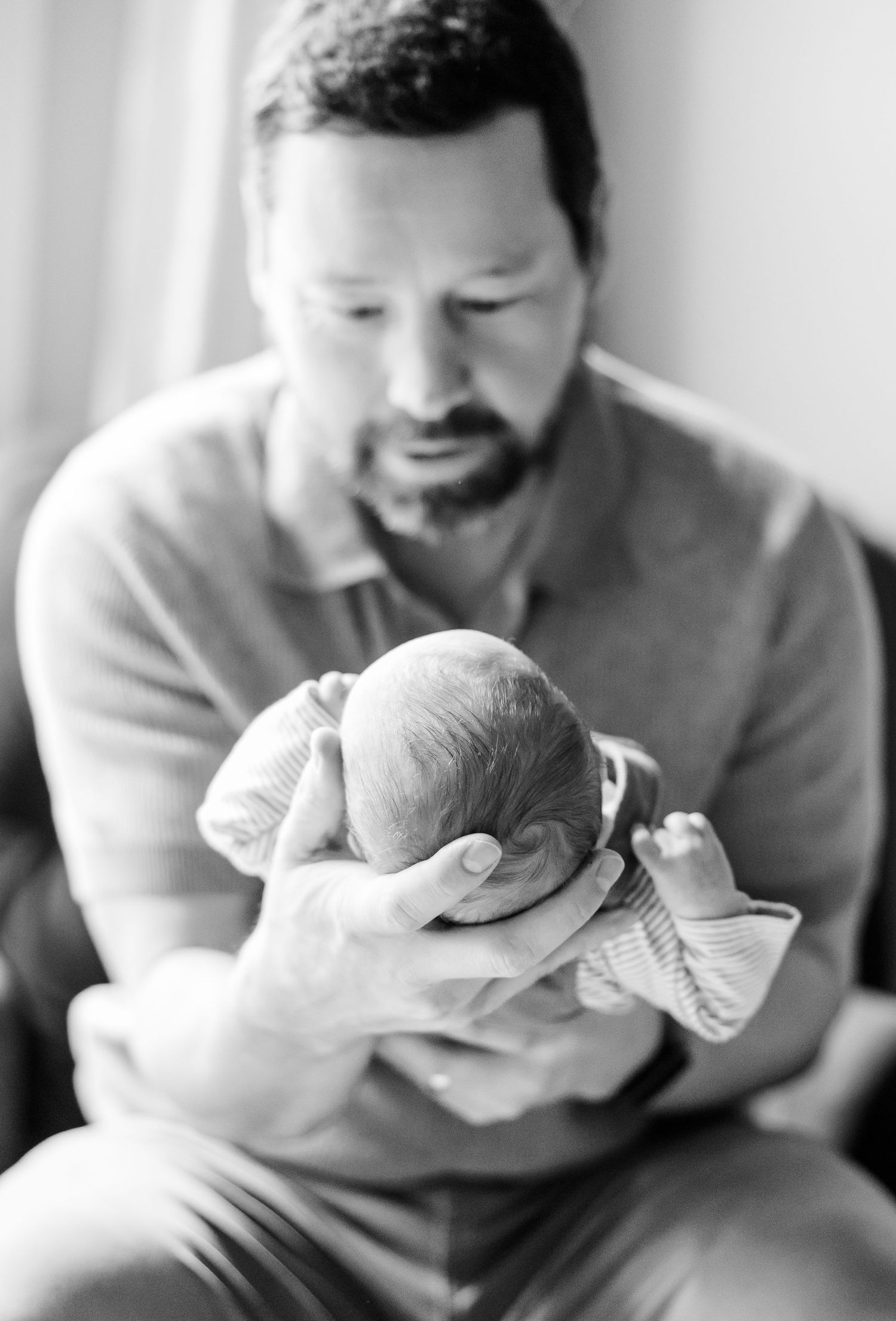 Black and white portrait of father holding newborn son during Crystal Lake lifestyle newborn session