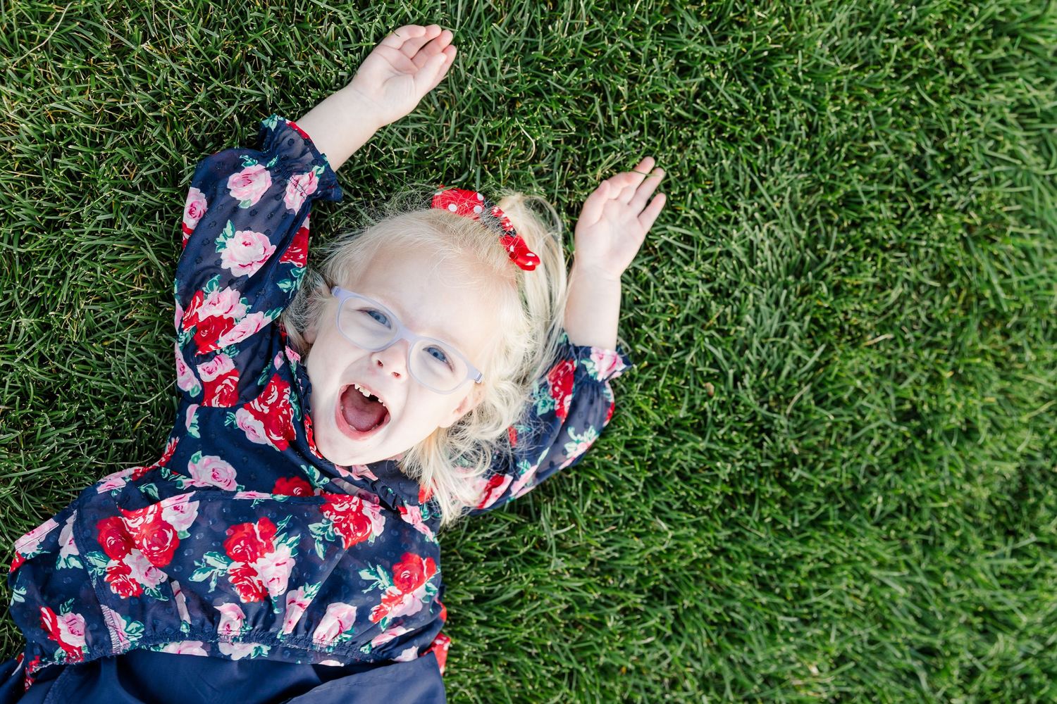 Caroline lying in the grass and laughing during her family’s outdoor summer portrait session.