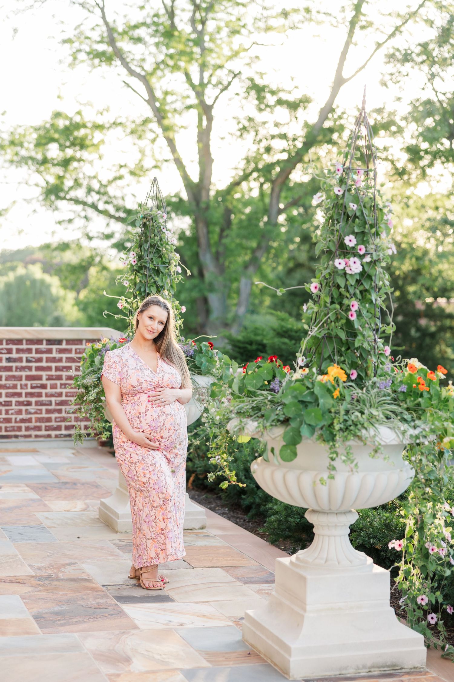 Solo maternity portrait by colorful flowers and brick garden walls at Cantigny Park in Wheaton Illinois