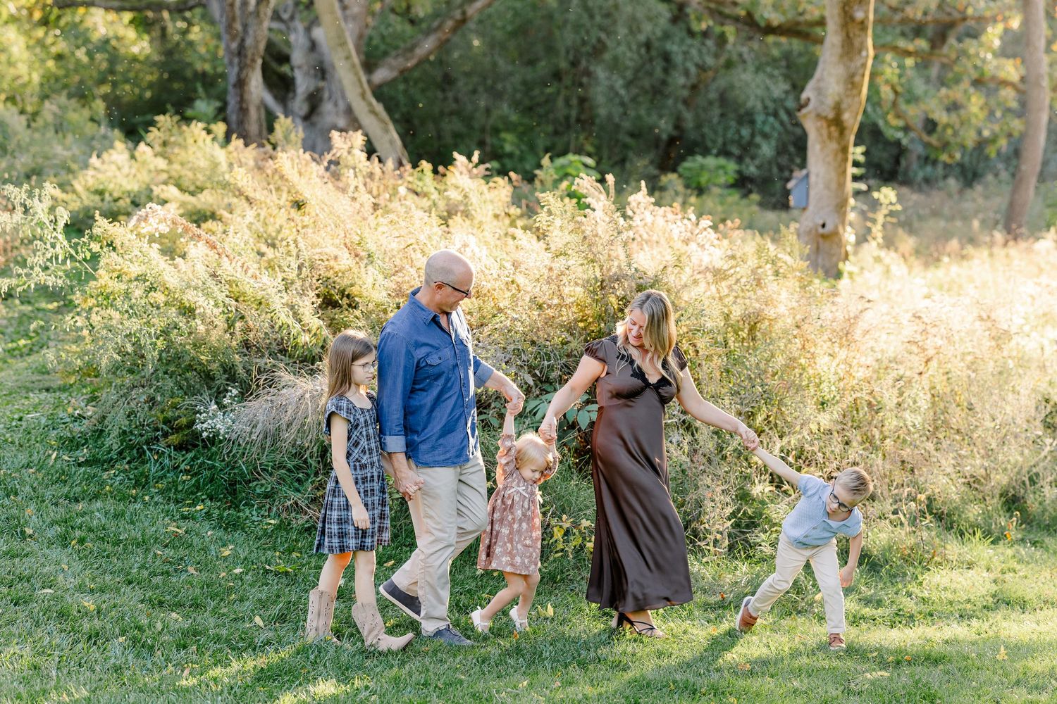 Family holding hands and playing together during fall family photos at home in St. Charles, IL.