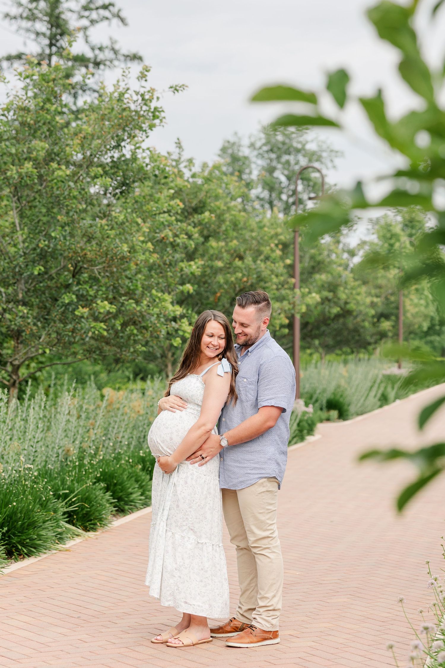 Expecting parents framed by greenery during a peaceful garden maternity session in Wheaton