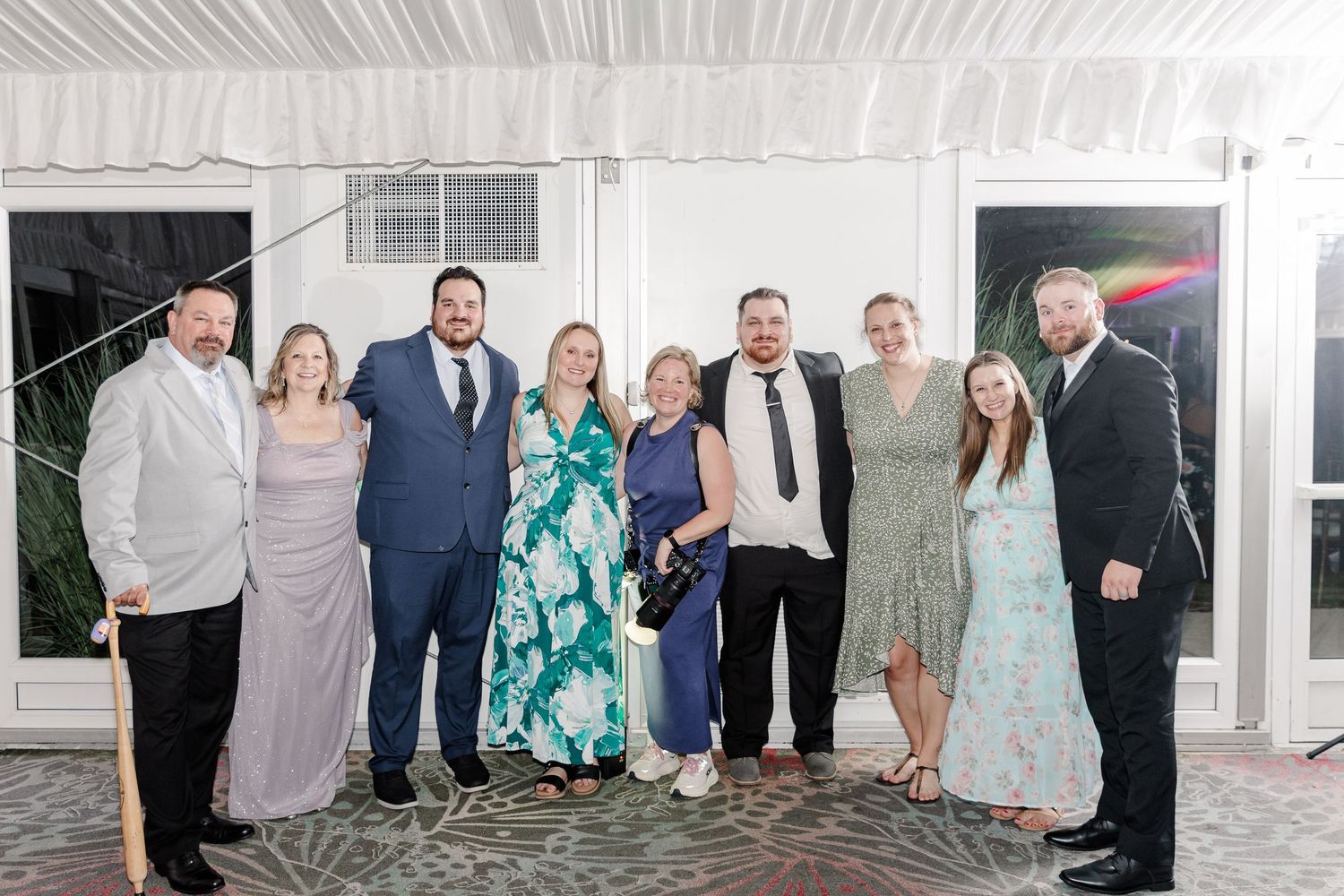 A group of eight wedding guests pose together for a photo at an elegant evening wedding reception.