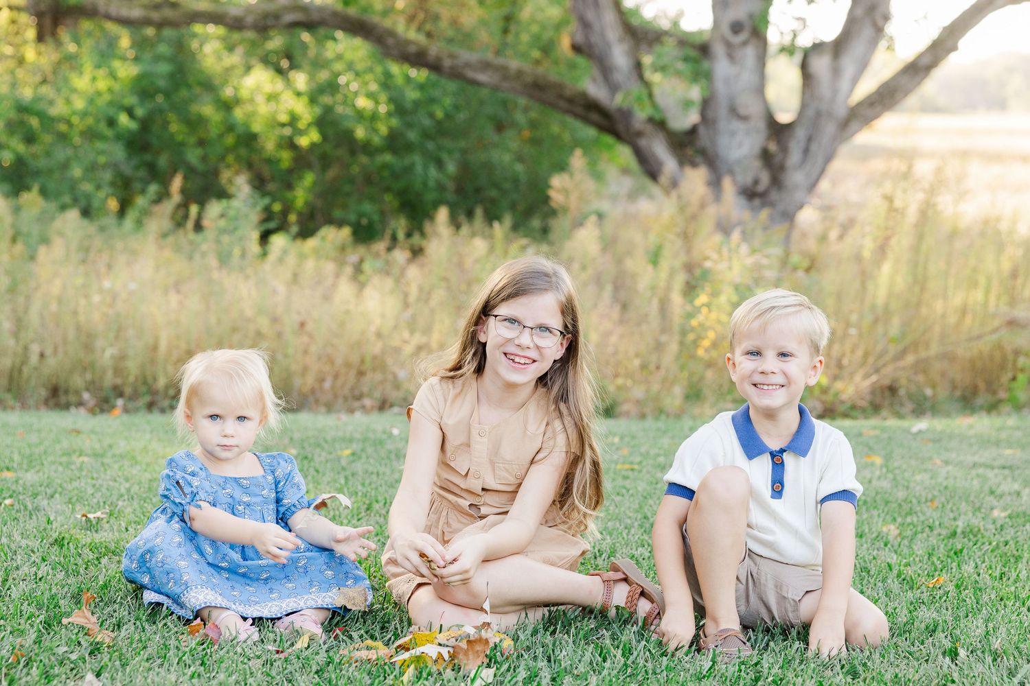Children sitting together on the grass during family portraits at home in St. Charles, Illinois
