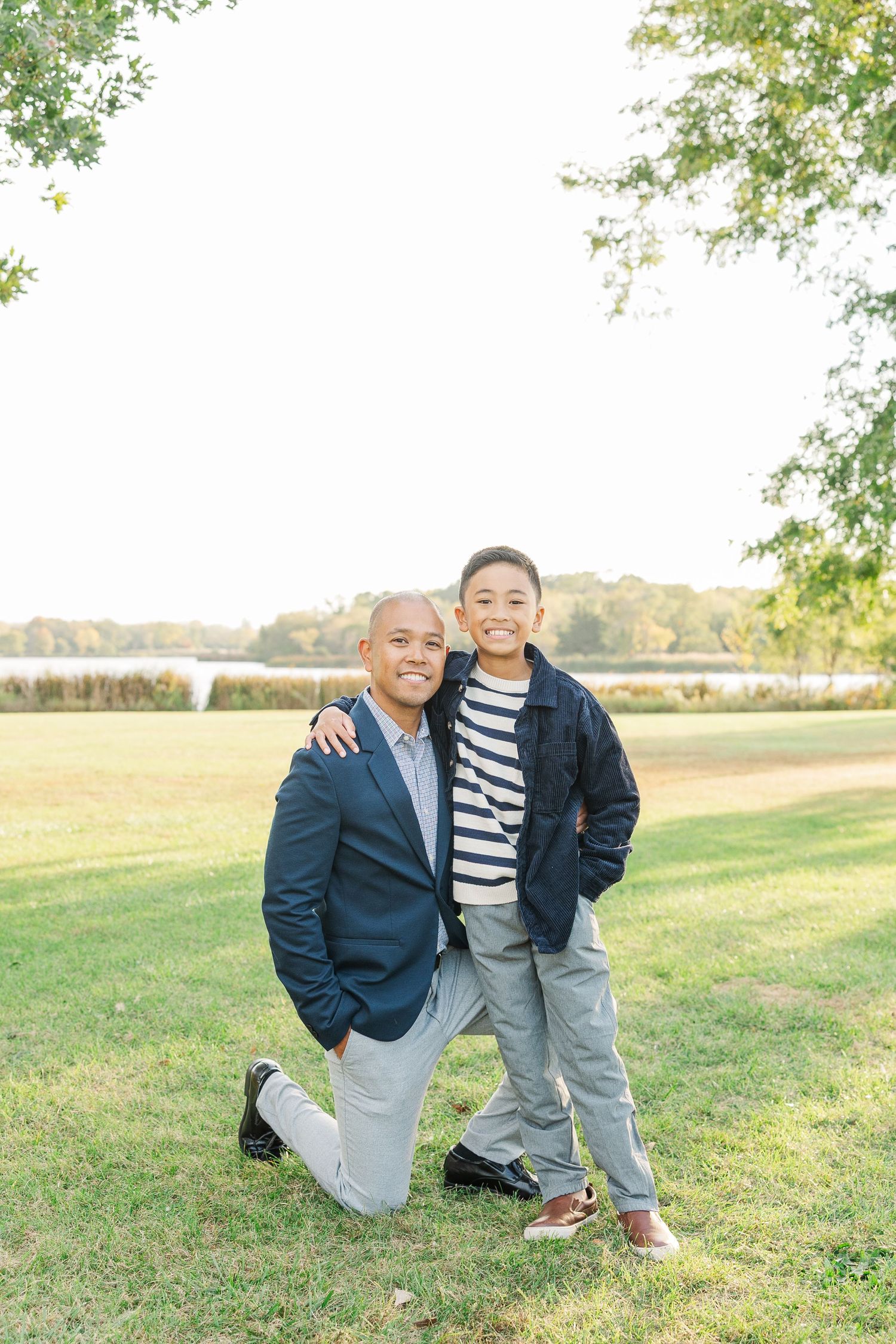 Two young children in coordinating navy jackets pose together on grassy field during autumn photoshoot. Busse Woods