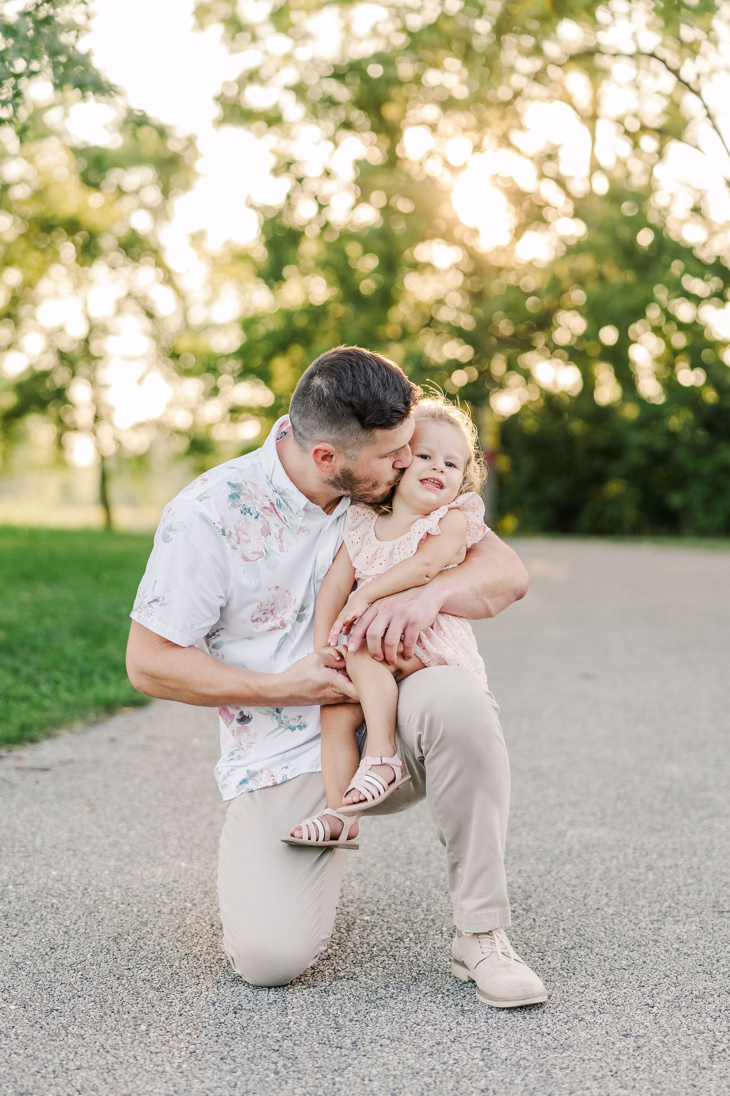 Tender moment captured between adult and child on sunny park path.