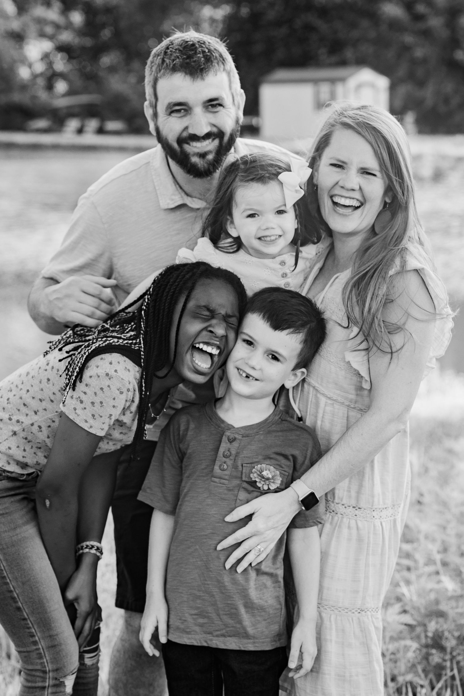 Black and white portrait of family sharing genuine laughter outdoors.