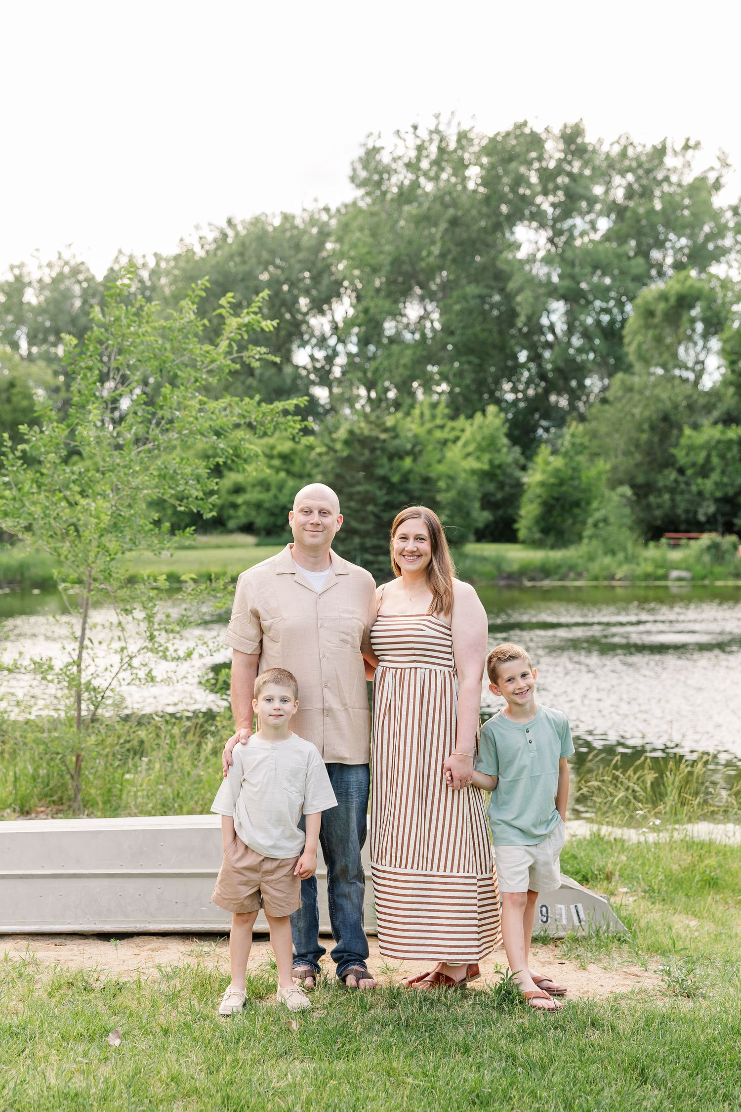 Family of four posing by the lake during a summer family photo session at Shamrock Hills Park in Crystal Lake, Illinois.