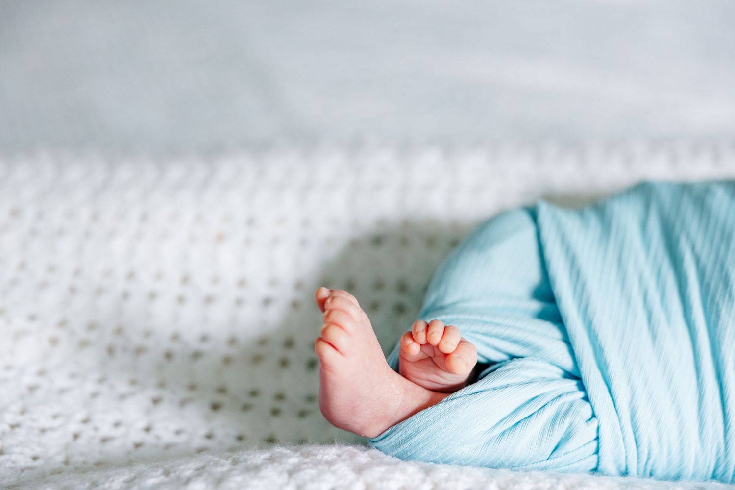 Close-up of newborn feet on bed during in-home lifestyle newborn session in Crystal Lake, Illinois
