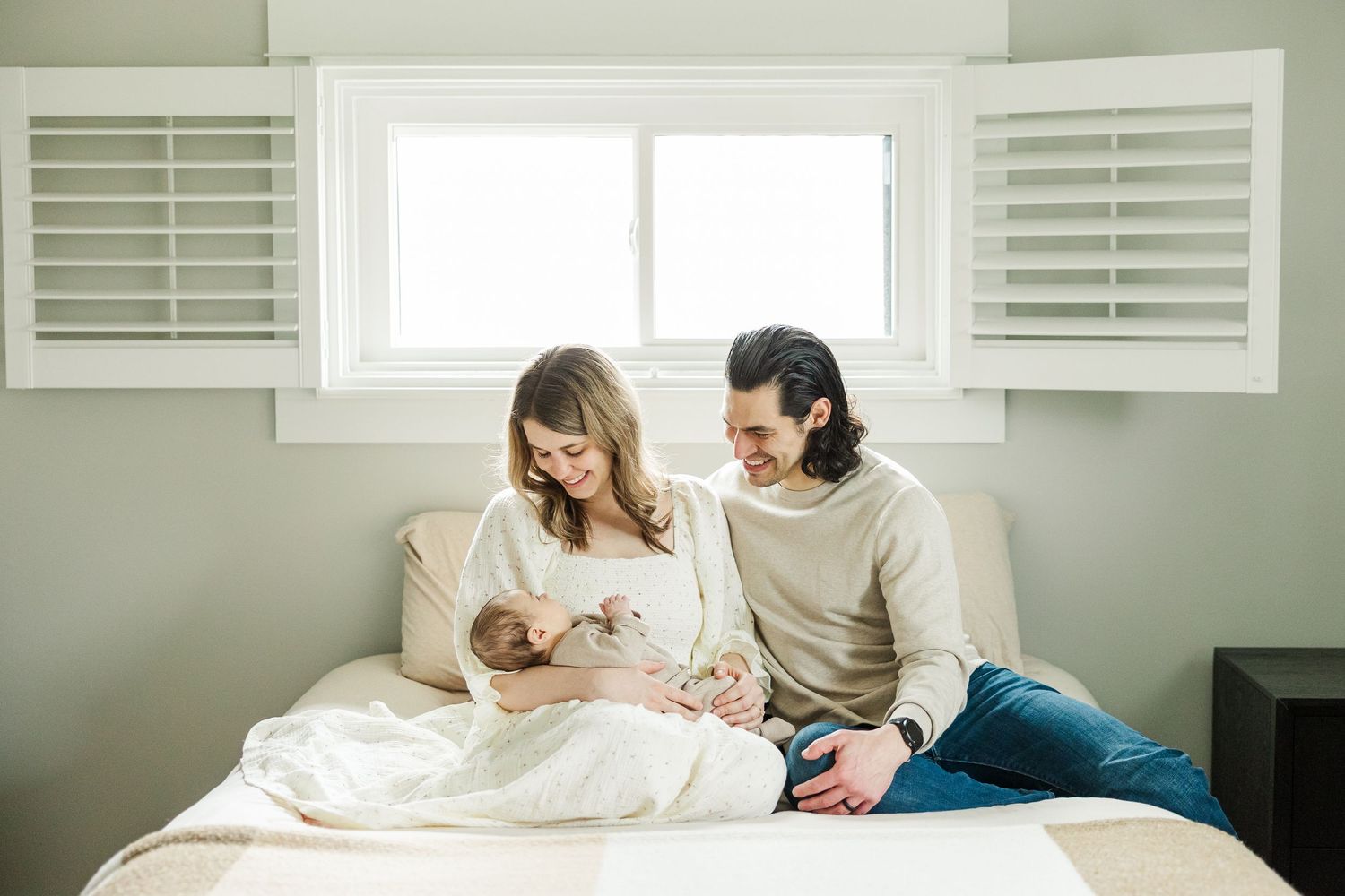 Lifestyle newborn photos in Palatine, Illinois of parents looking at newborn on bed