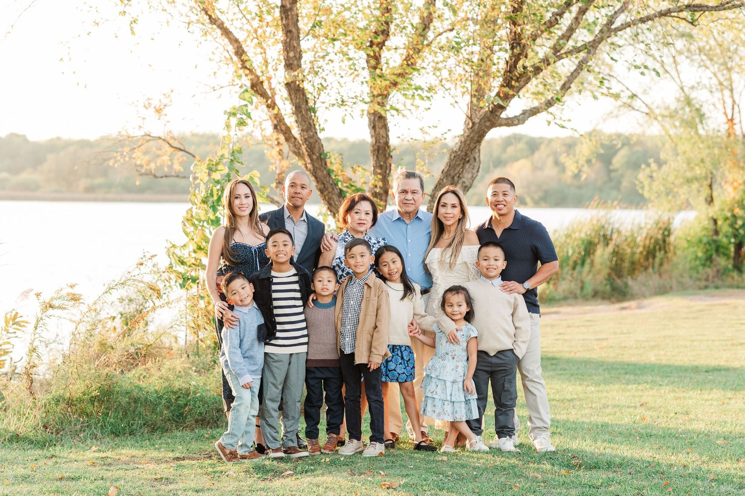 Extended family poses together on grassy hillside during golden hour sunset for outdoor portrait session. Busse Woods