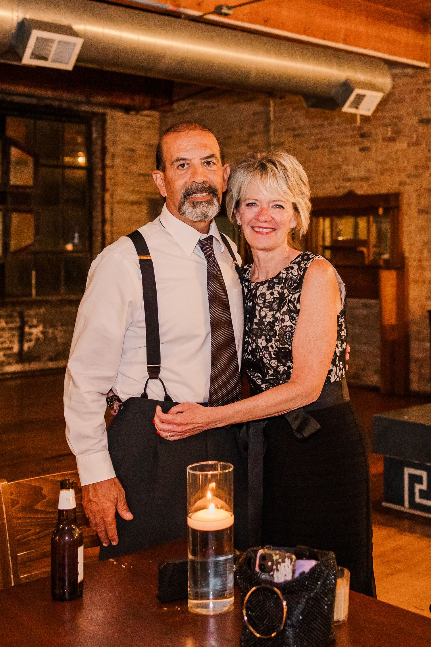 Couple posing by candlelight in an industrial-style venue with exposed brick walls.