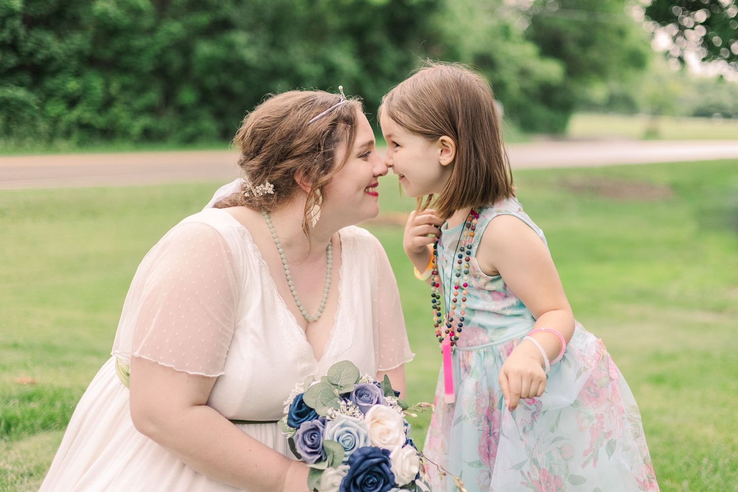Sweet moment between people sharing laughter on a grassy lawn with a bouquet.