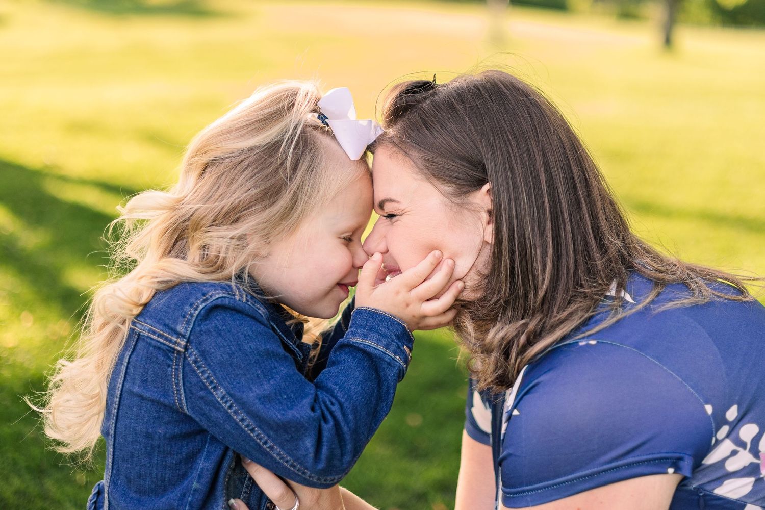 Two people share a sweet embrace in a sunlit outdoor setting with golden bokeh background.