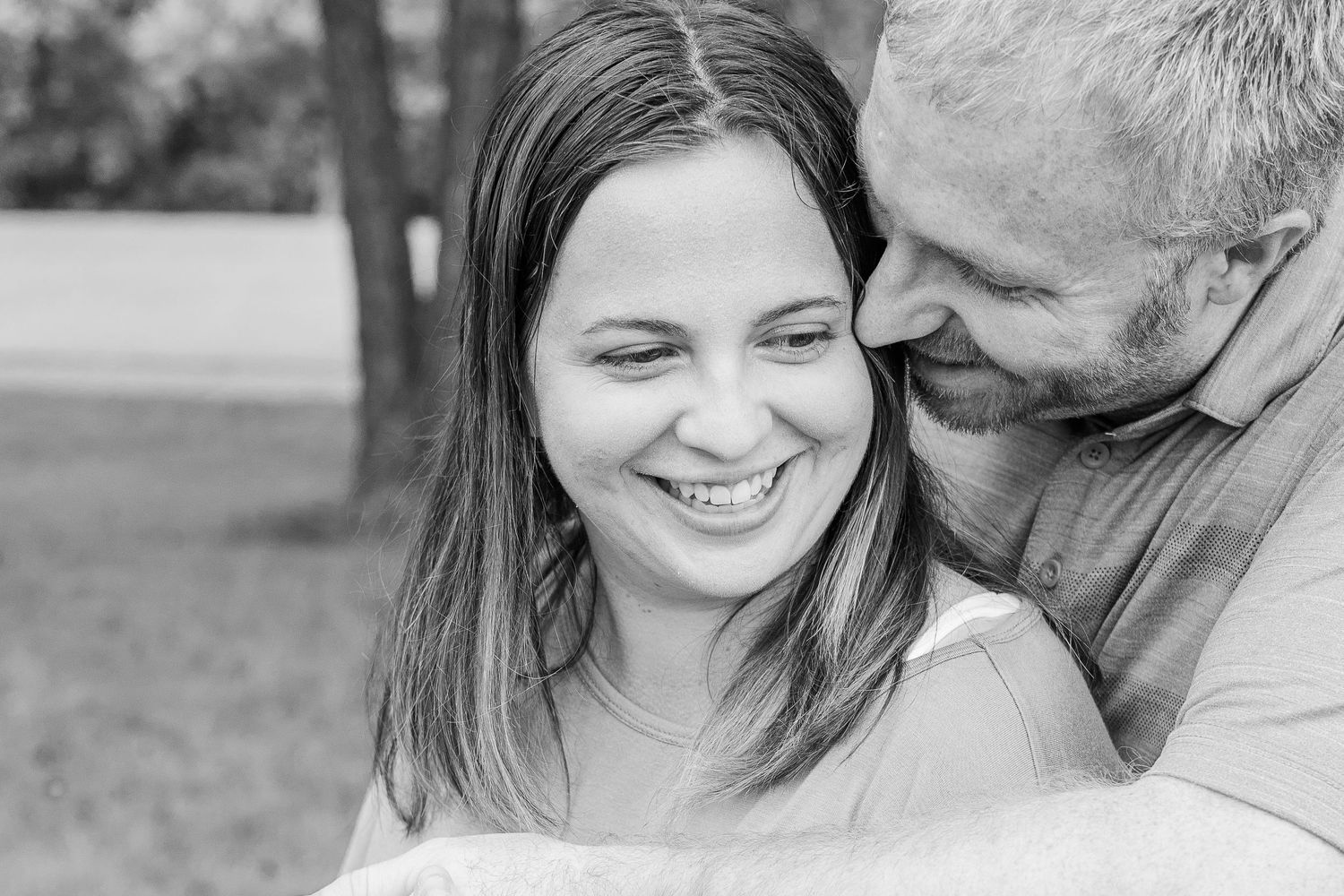 A black and white portrait captures a tender moment between a happy couple.