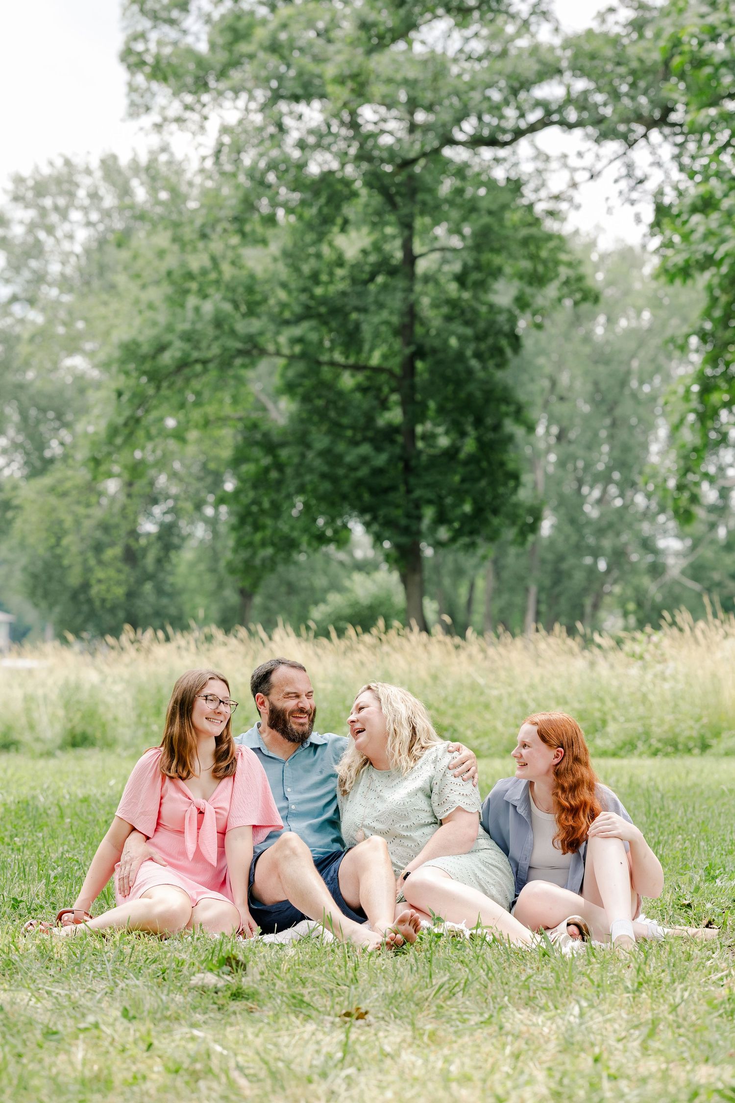 Family sitting together in the grass for a relaxed summer portrait session in Crystal Lake, Illinois.