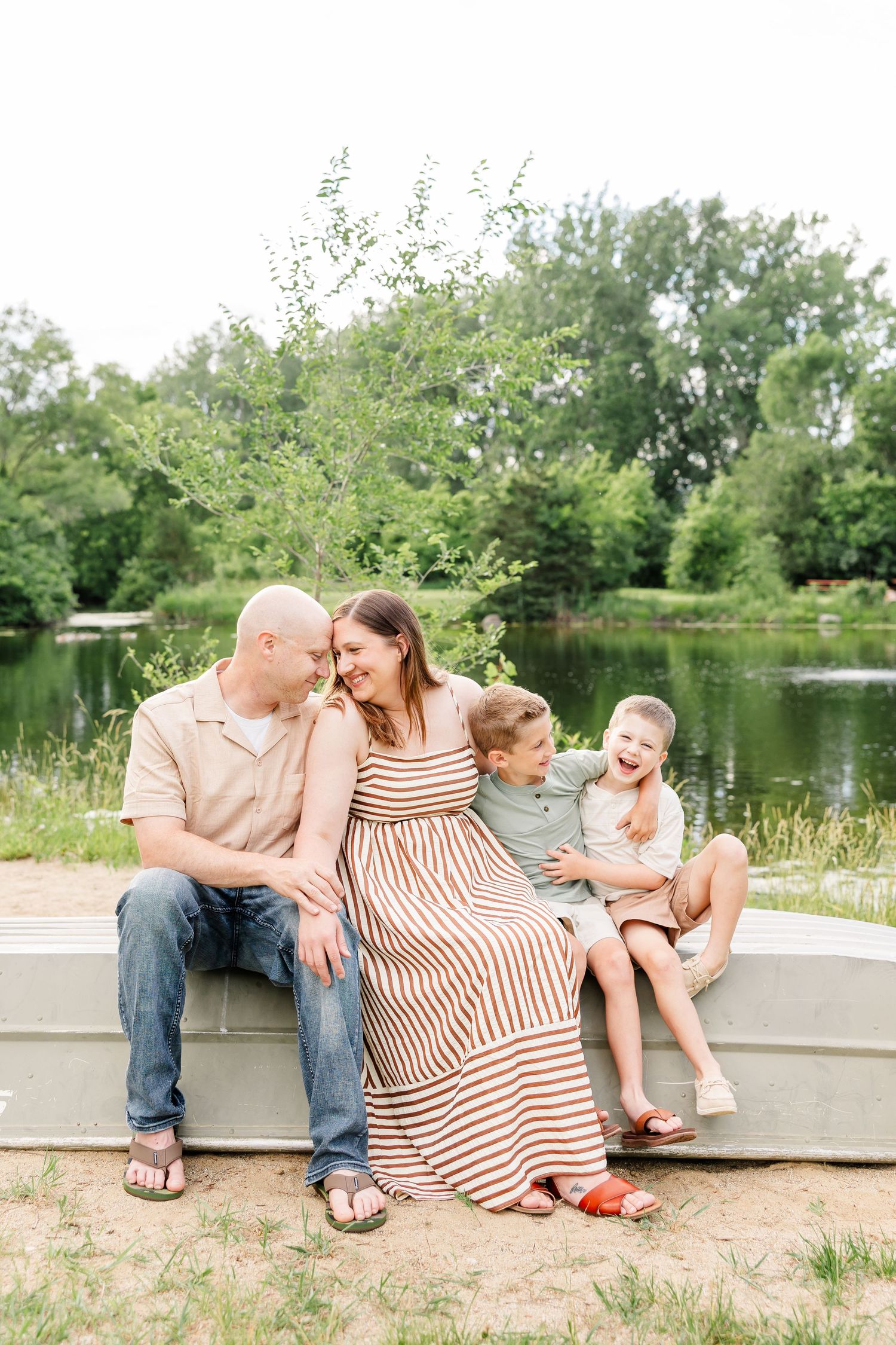 Mom and dad cuddling with their sons during a sweet family photo session by the water in Crystal Lake, Illinois.
