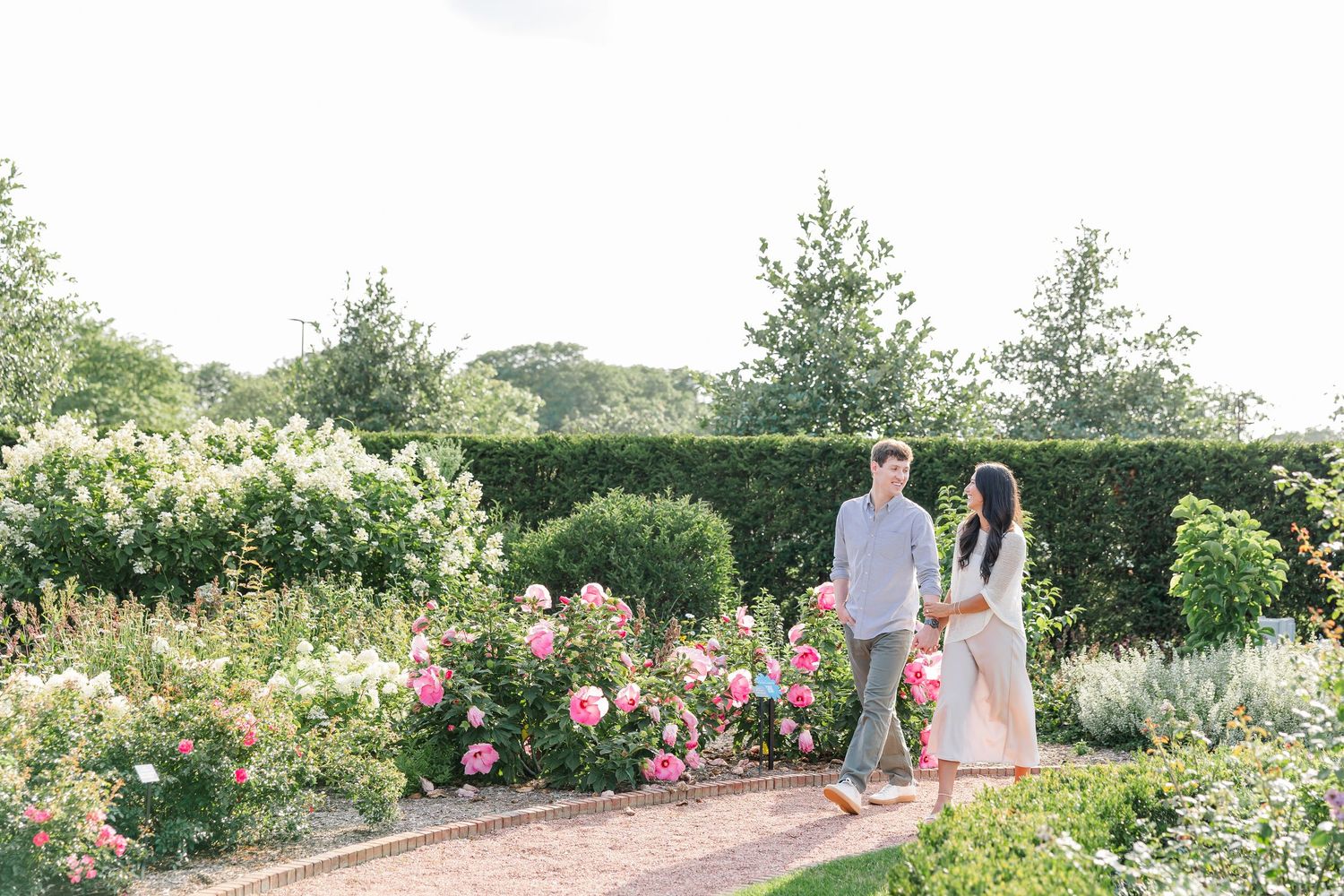 Wide portrait of Alysia and Jack sitting together among the blooming gardens.
