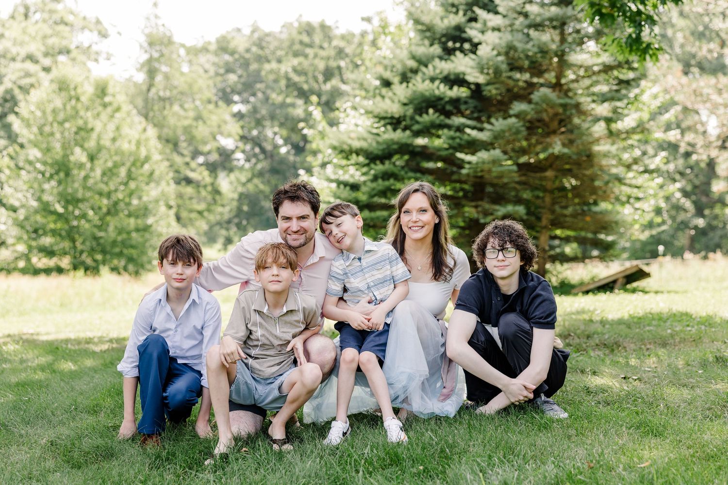 Large family sitting together outdoors during a summer extended family session in Crystal Lake, Illinois.