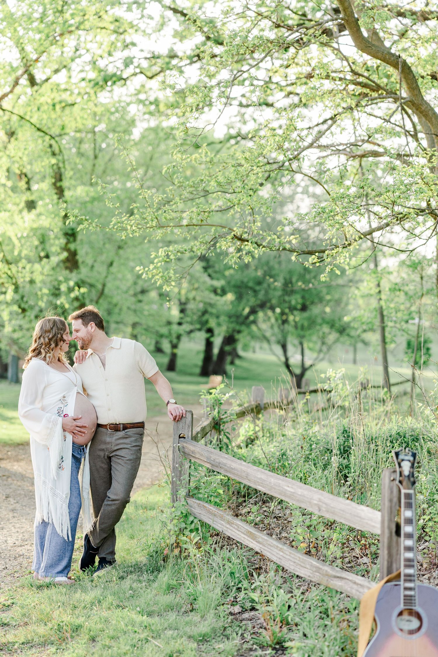 Expecting parents walking by a wooden fence during a maternity session at Veterans Acres Nature Preserve.