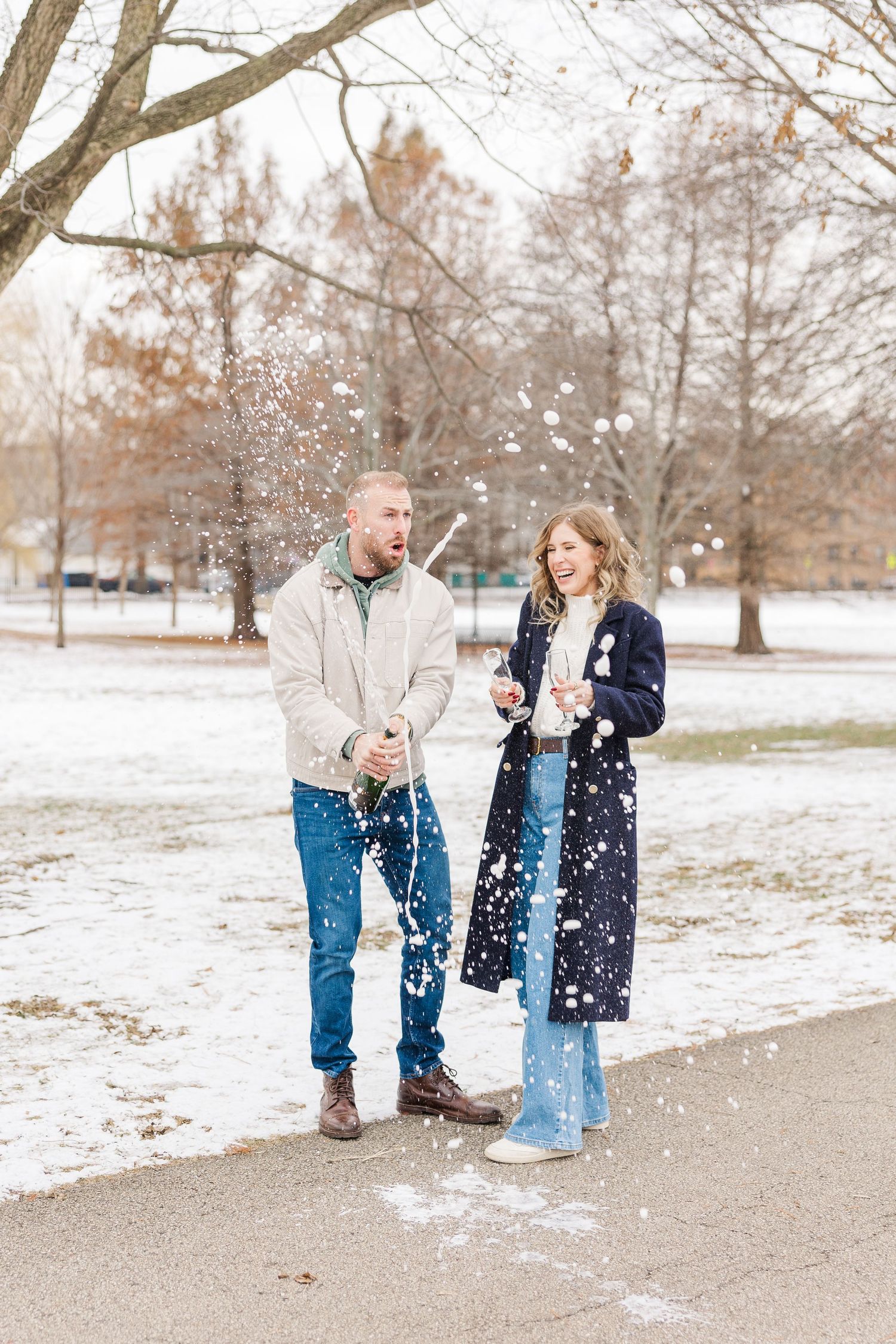 a couple pops champagne in Winnemac Park to celebrate their engagement in Winter