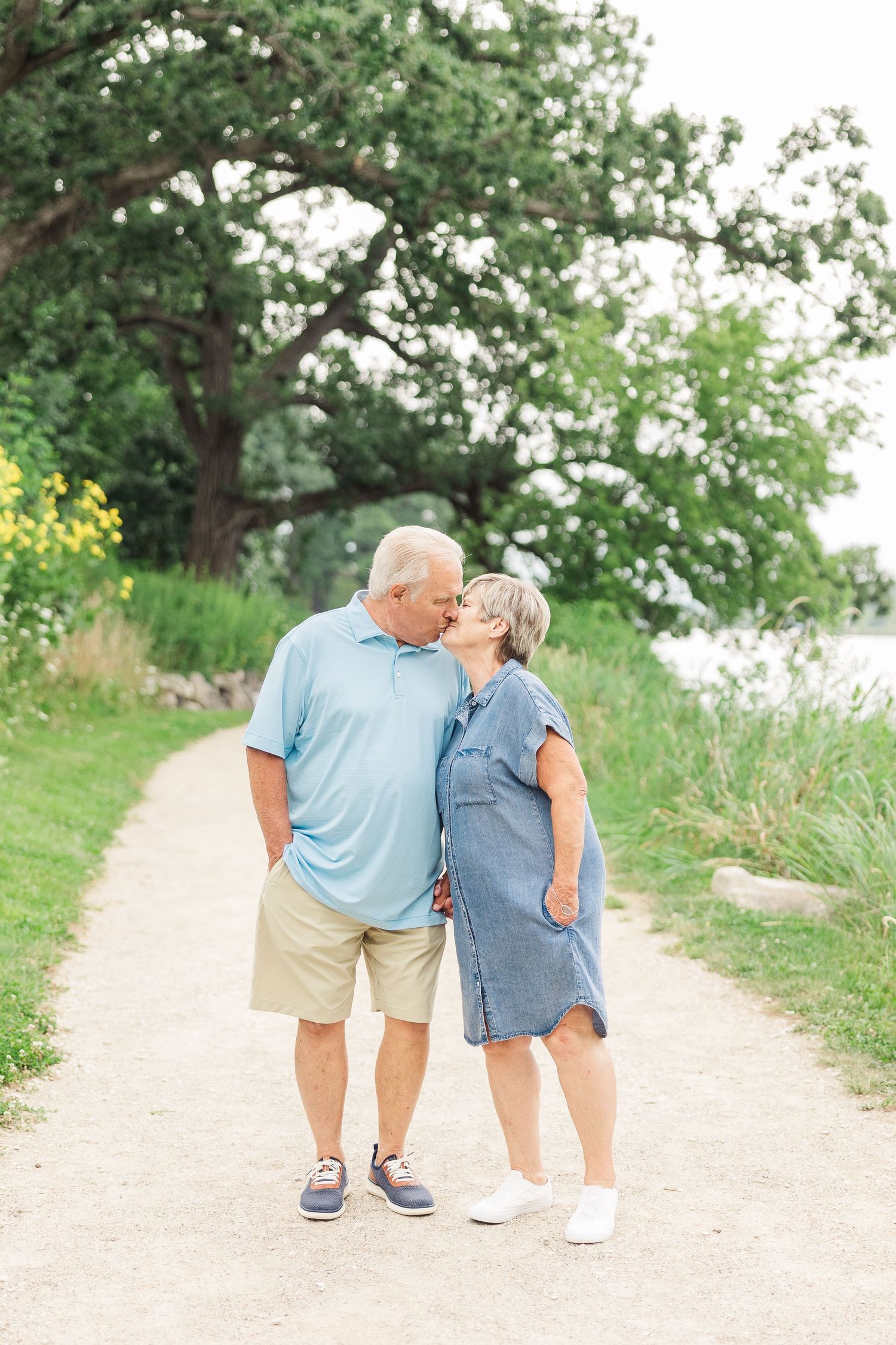 Couple sharing an affectionate moment while walking along a scenic path by the water.