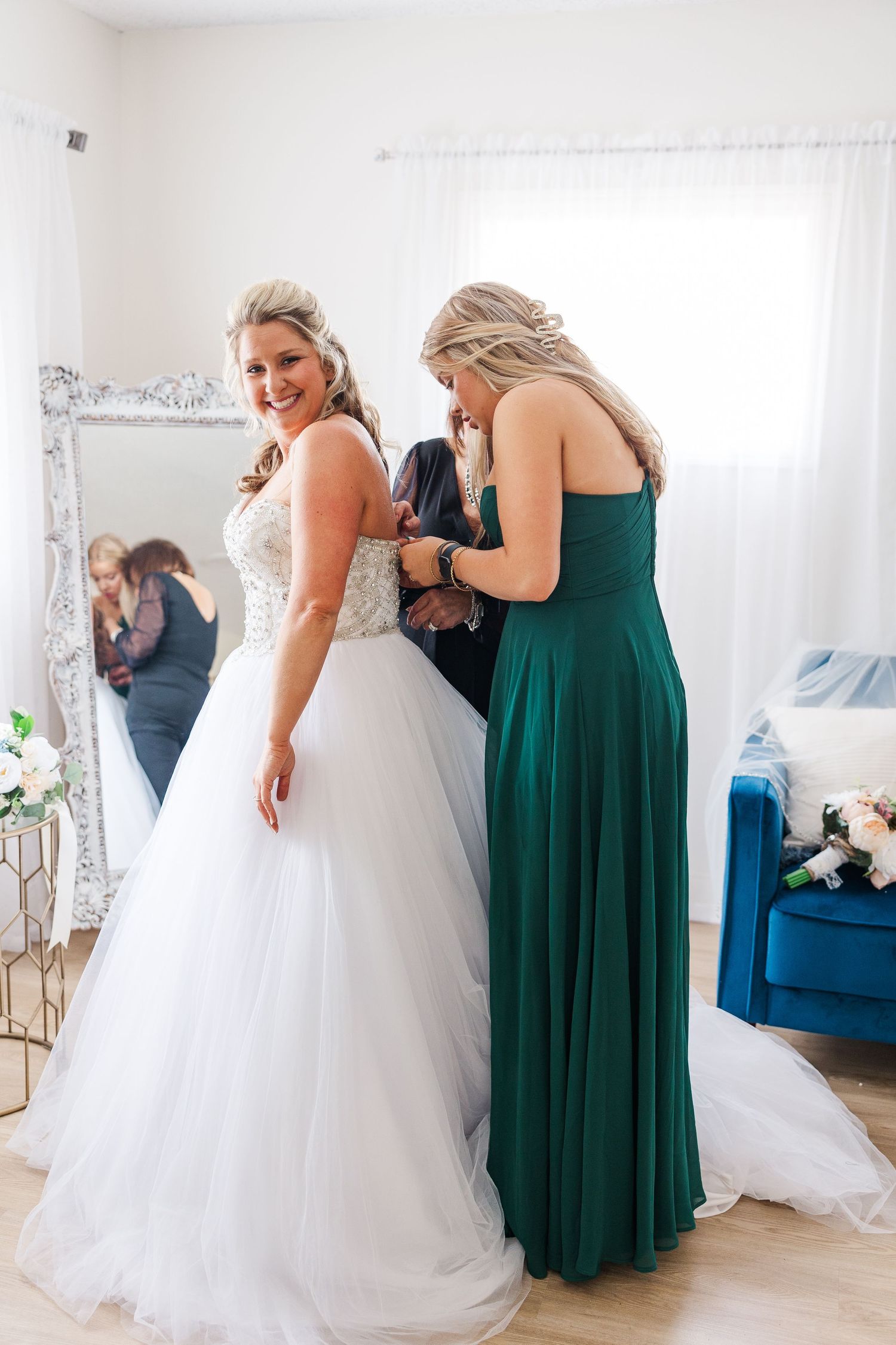 Elegant formal dresses in emerald green and white in bright dressing room.