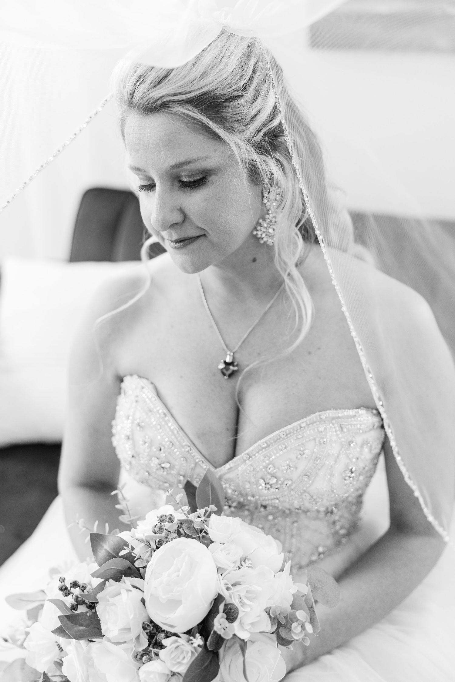 Black and white portrait of bride wearing strapless gown and holding white rose bouquet.