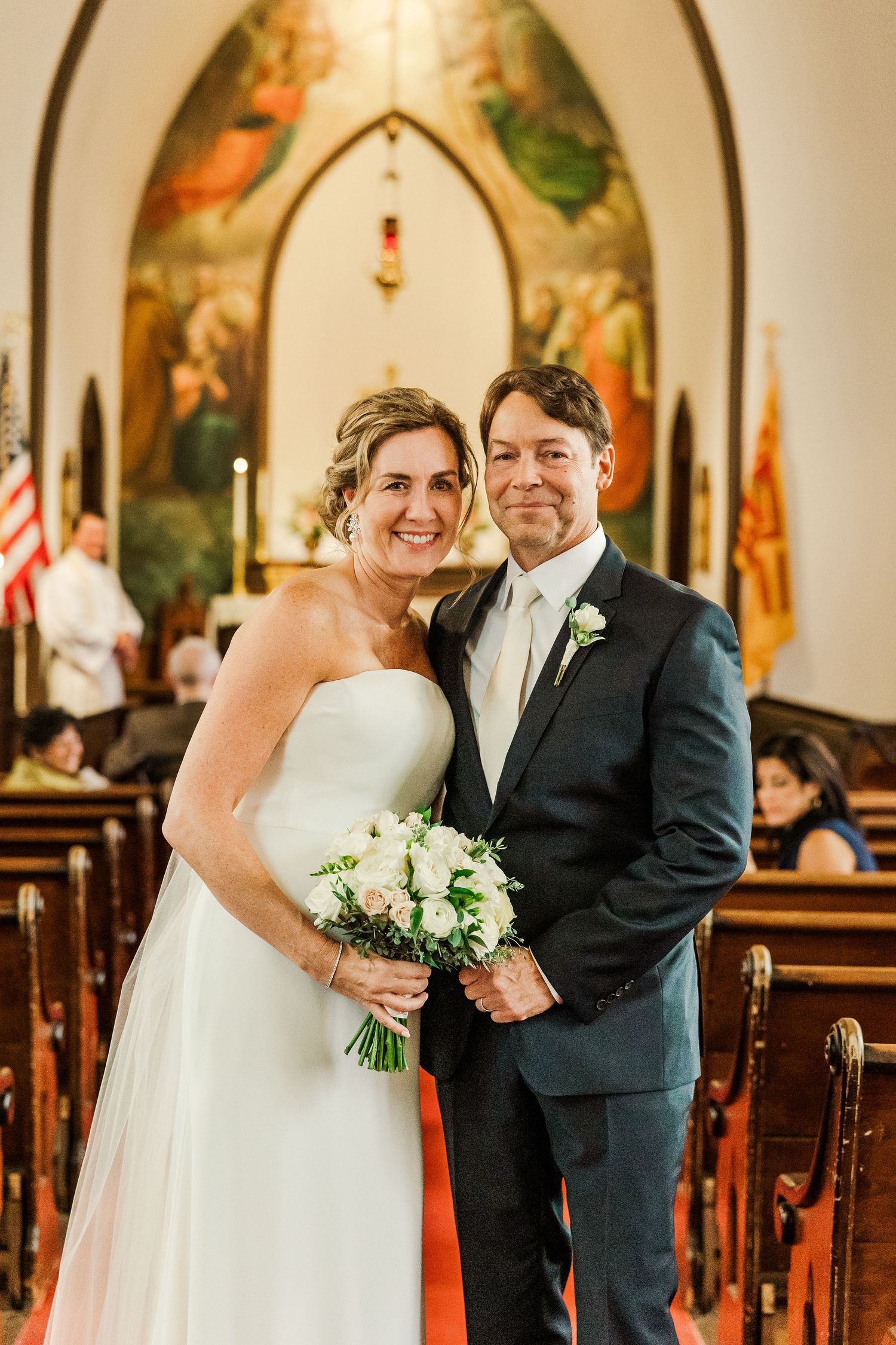 Wedding portrait in church sanctuary with religious murals and stained glass windows.