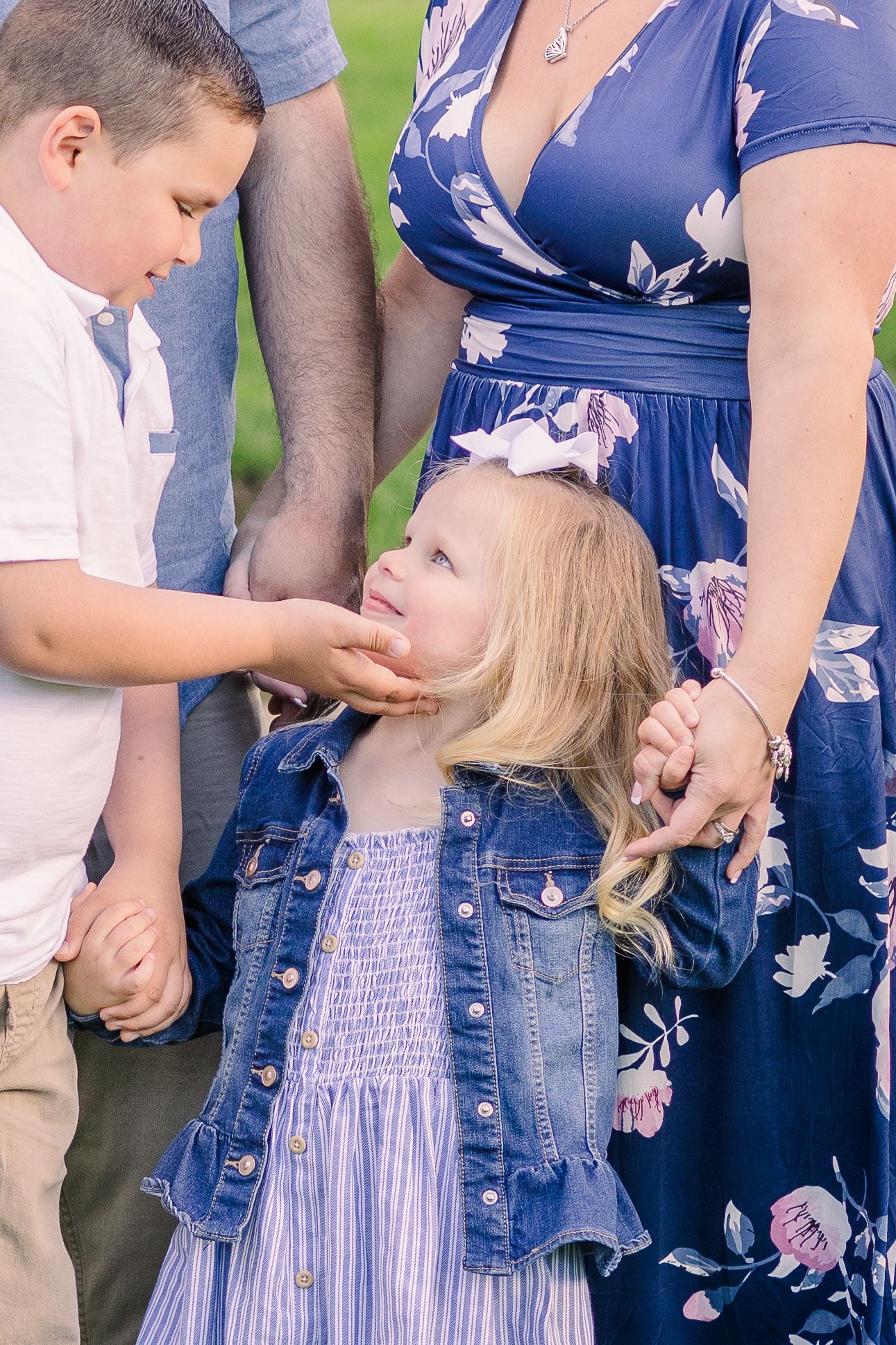 Close up of family members wearing coordinating blue and white outfits standing together outdoors.