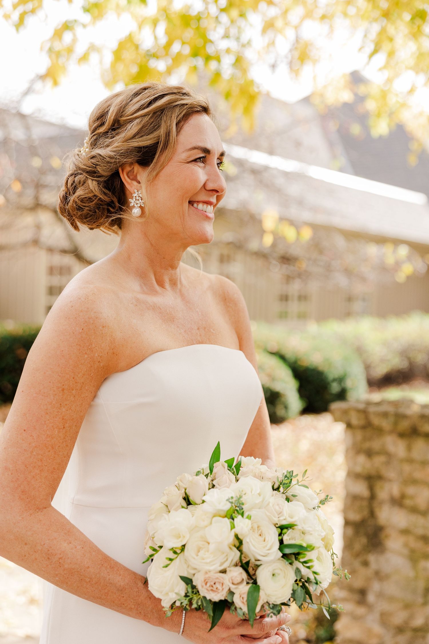 Elegant bridal portrait in autumn garden setting with white bouquet.