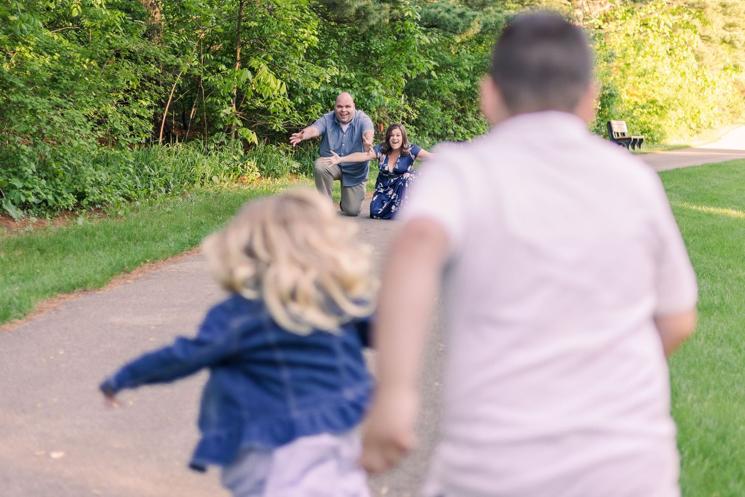 Motion blur photograph of people walking on a paved trail through a wooded park.
