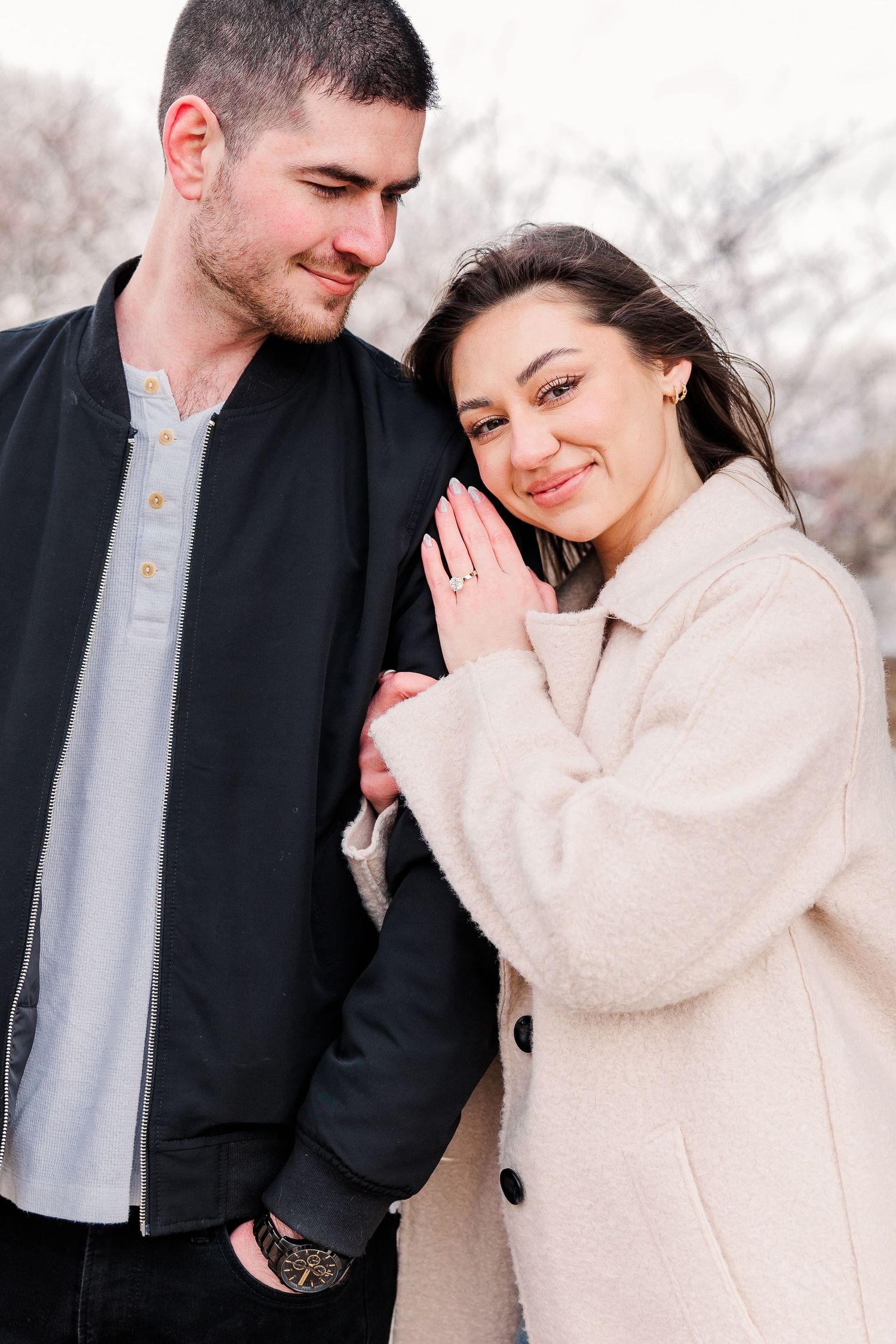A couple in winter coats sharing an affectionate moment against a winter backdrop.