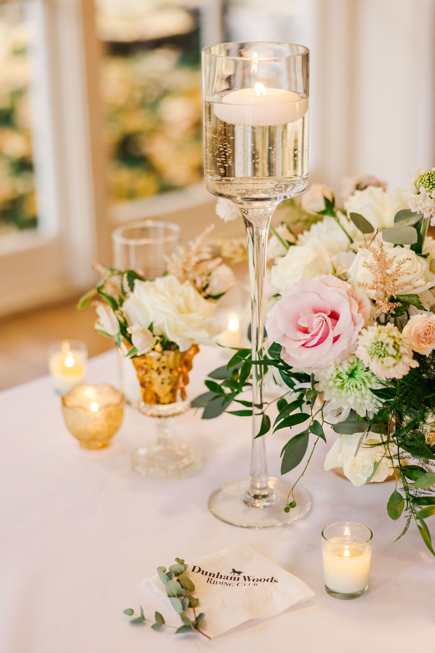 Elegant table setting with champagne, candles, and pink and white floral centerpiece.