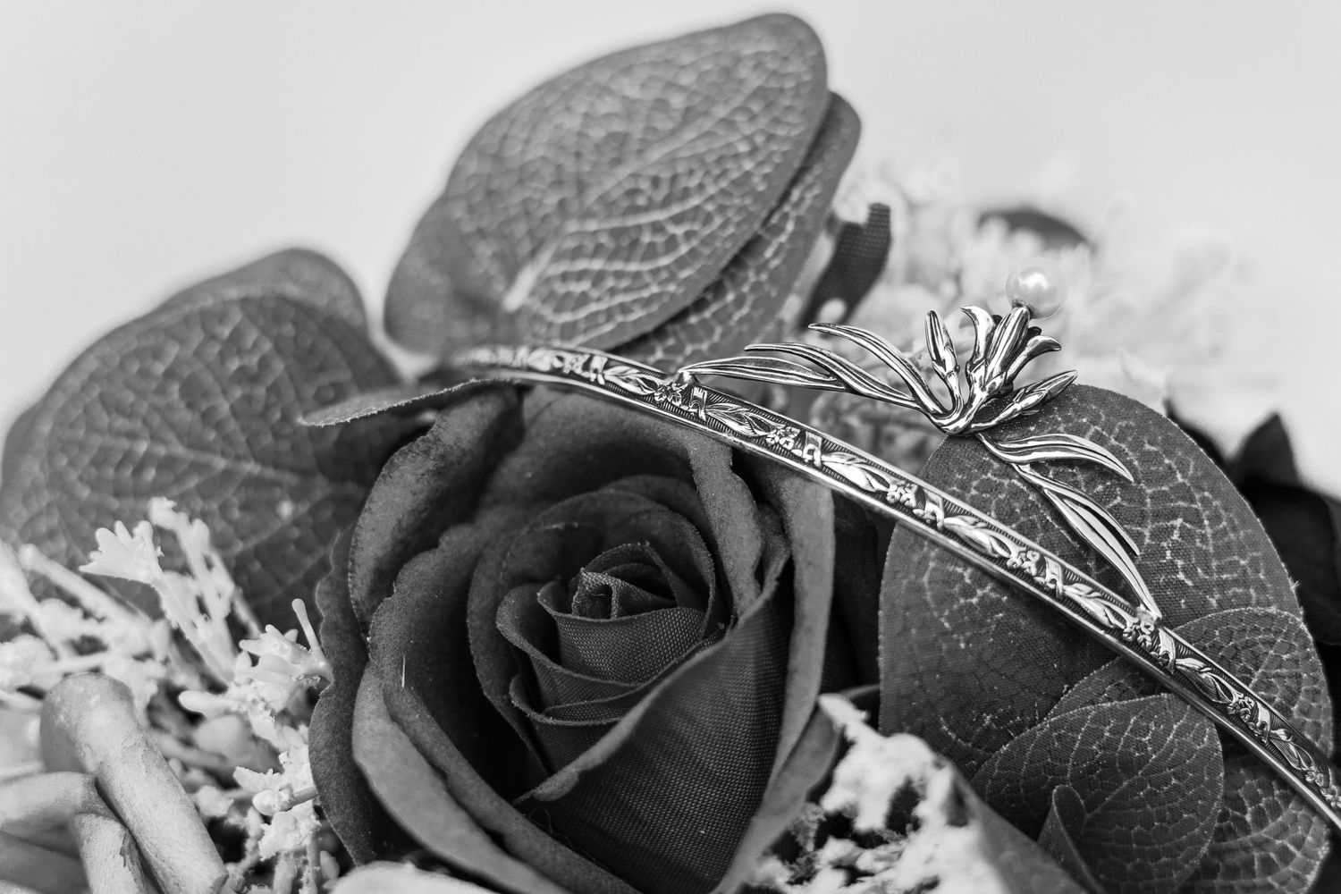 Black and white photo of a vintage-style tiara resting on roses.