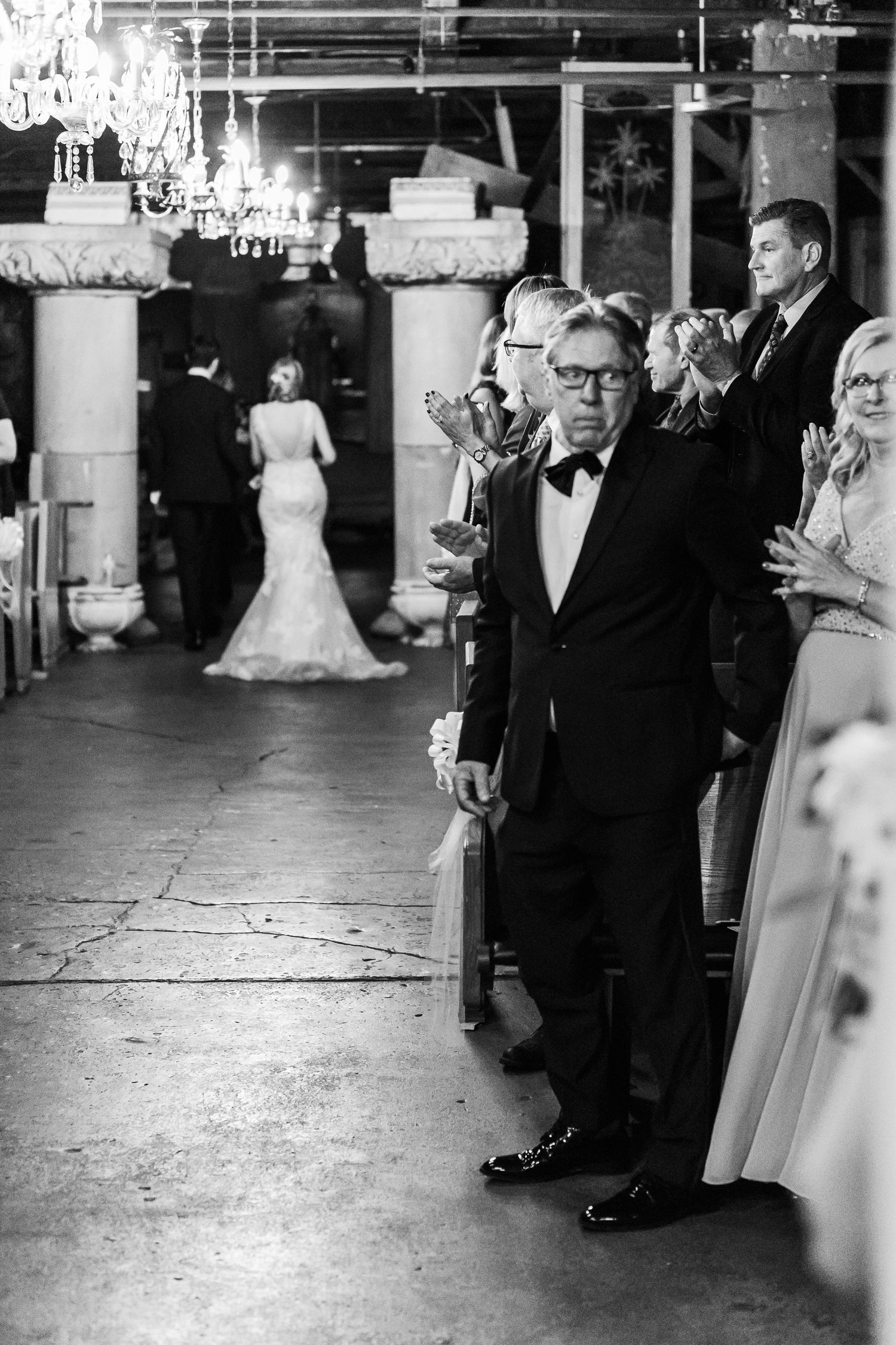 Indoor wedding reception with elegant chandeliers and guests in formal attire.