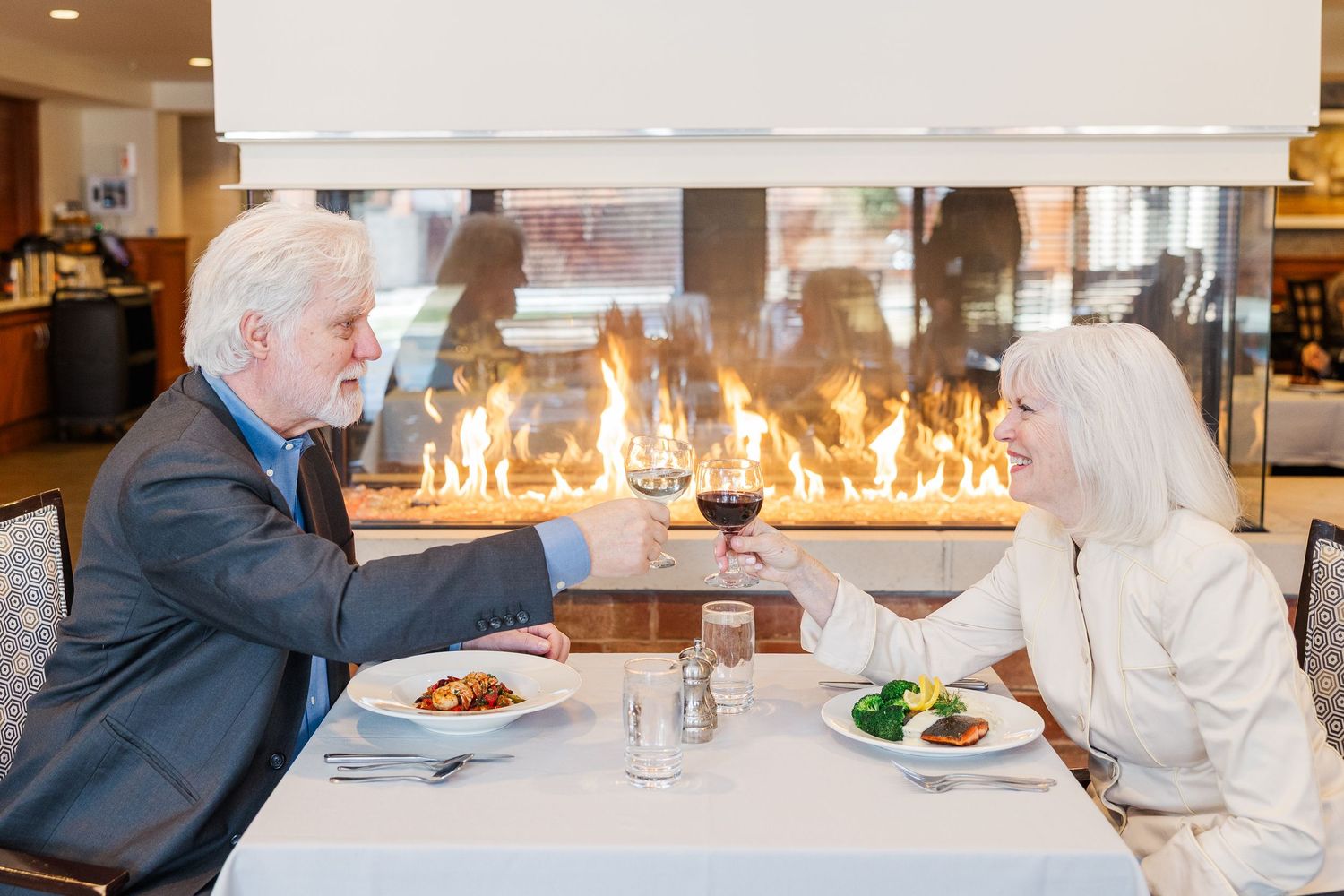 Beacon Hill senior living branding photo in Lombard, Illinois featuring couple dining by fireplace