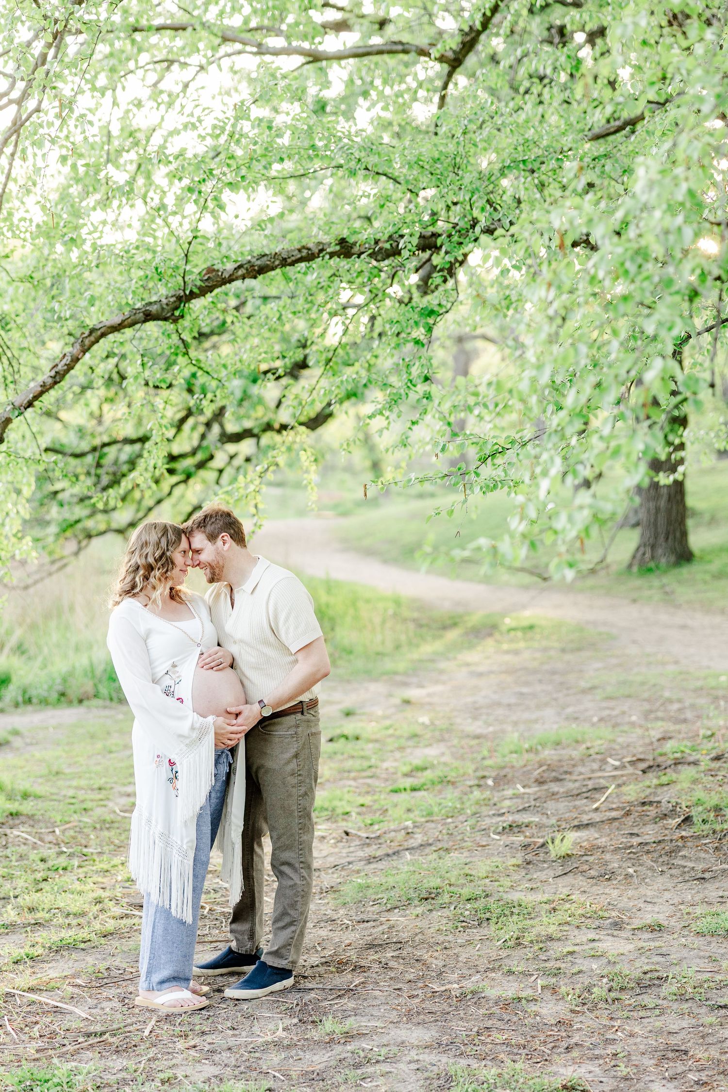 Expecting parents holding baby bump during a golden hour maternity session at Veterans Acres in Crystal Lake.