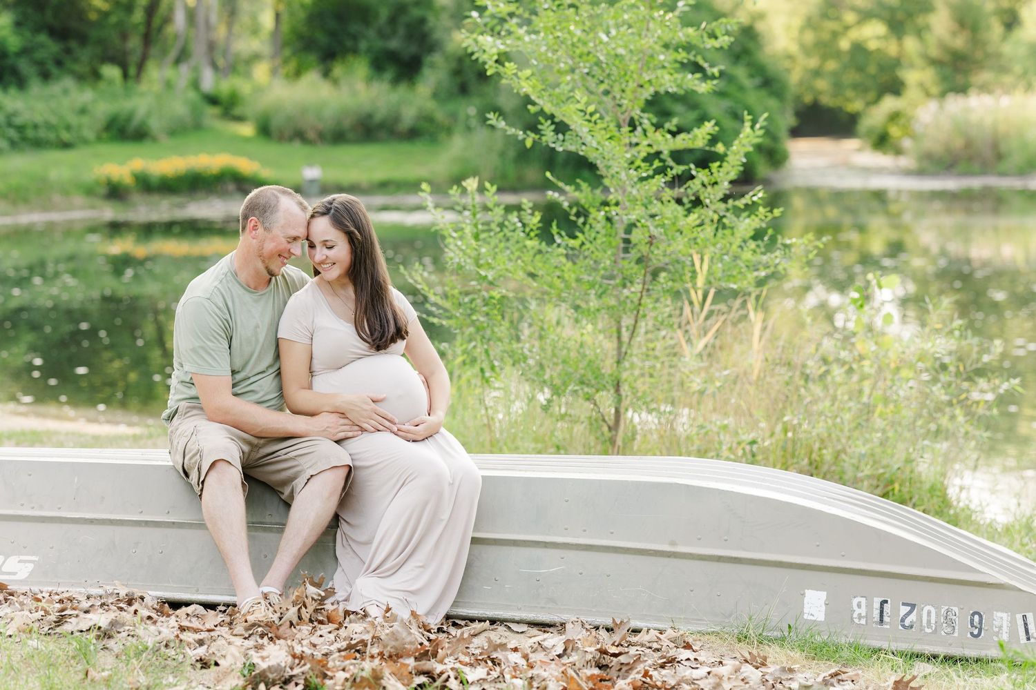 Expecting couple sitting together with hands on baby bump during family maternity session at Shamrock Hills Park in Crystal Lake IL