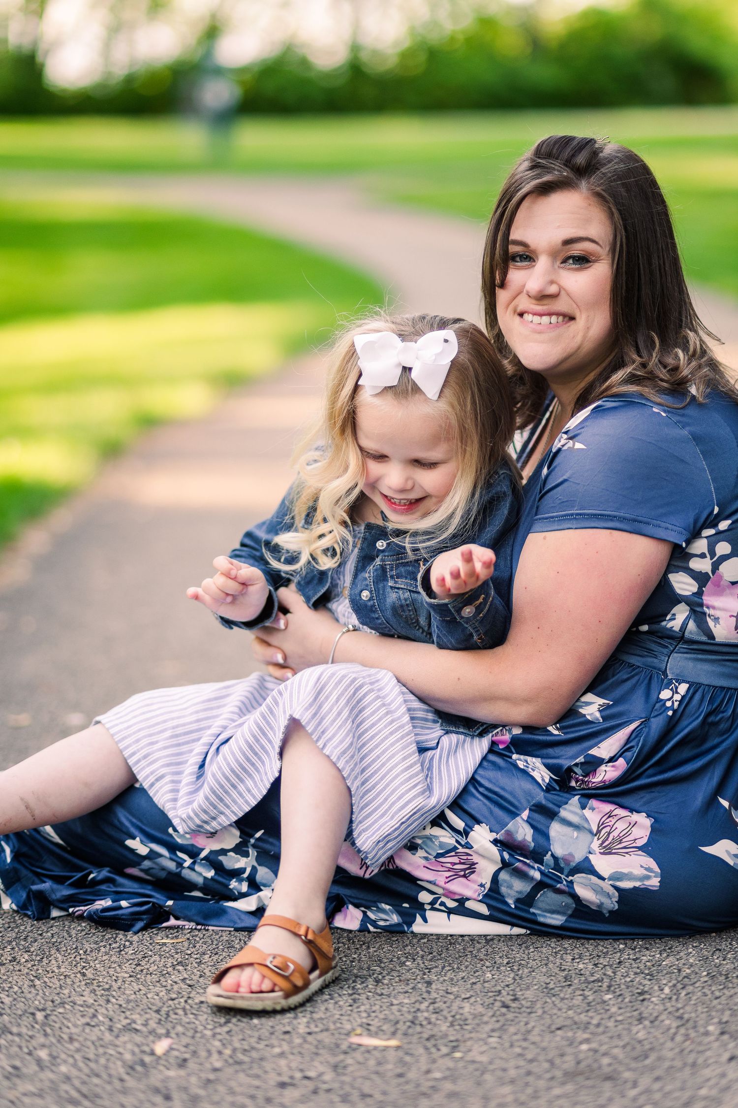 A joyful moment shared on a park pathway surrounded by green grass on a sunny day.