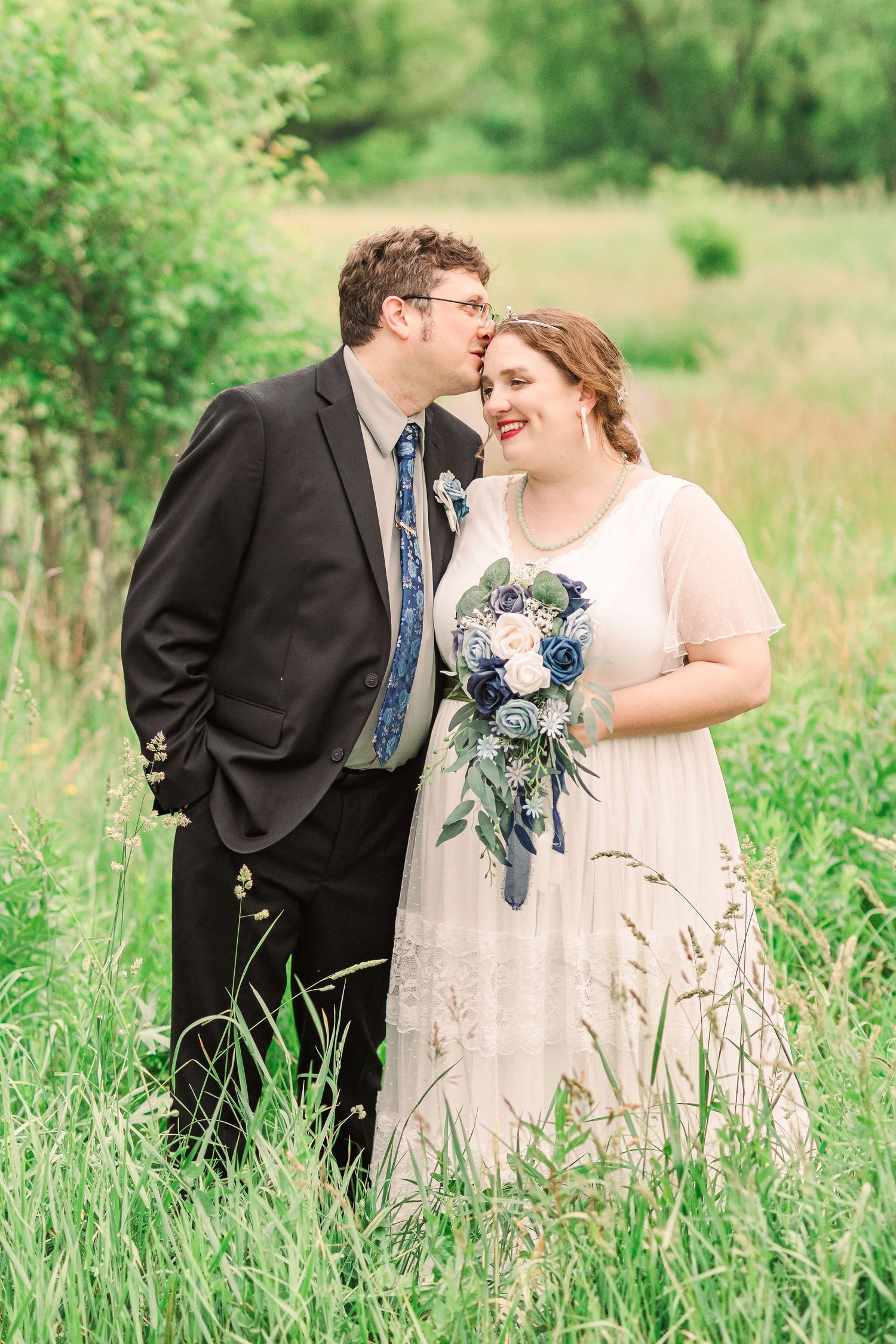 Romantic candid moment between newlyweds laughing together in a sunny meadow.