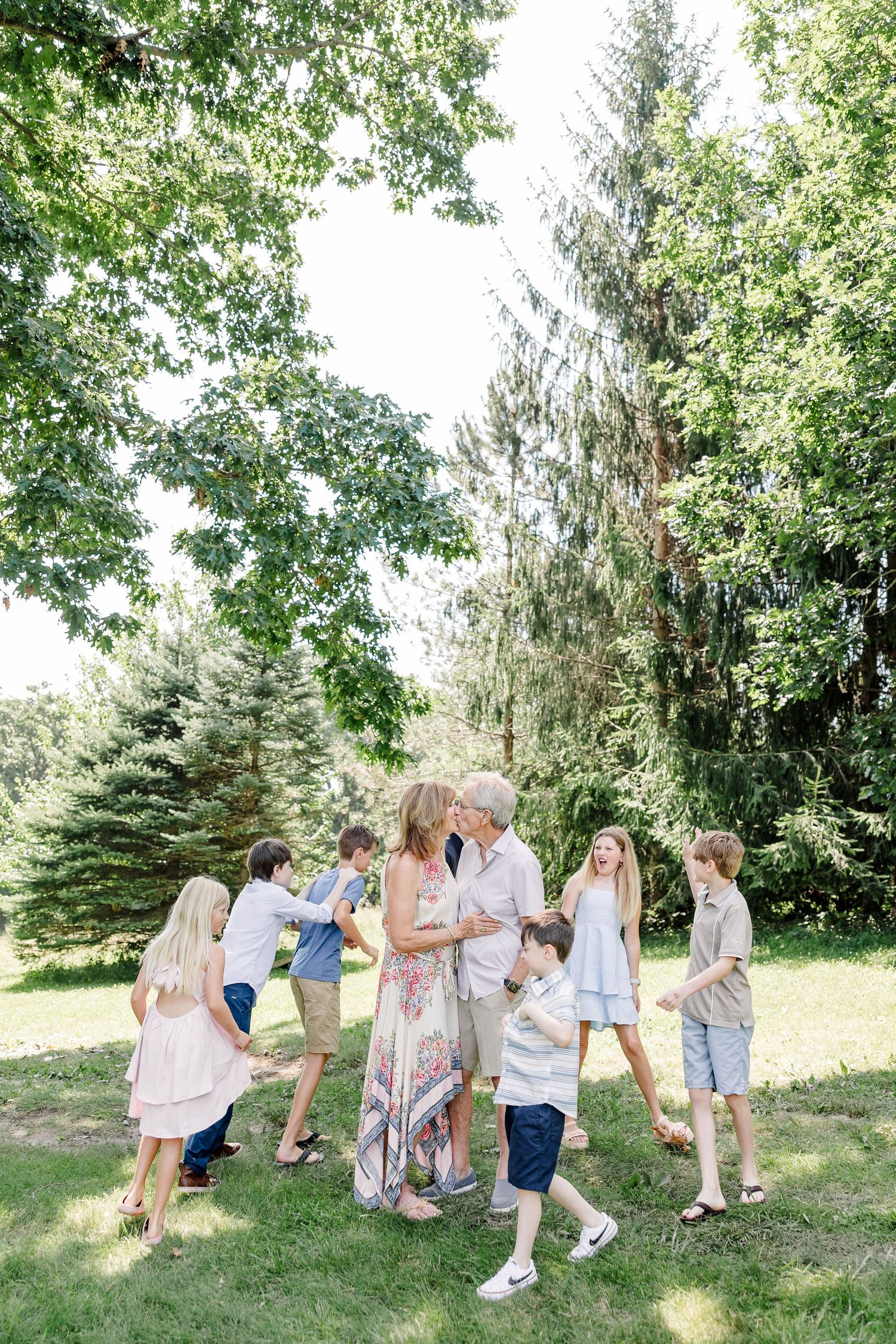 Candid family moment under the trees during a summer extended family session in Crystal Lake, Illinois.