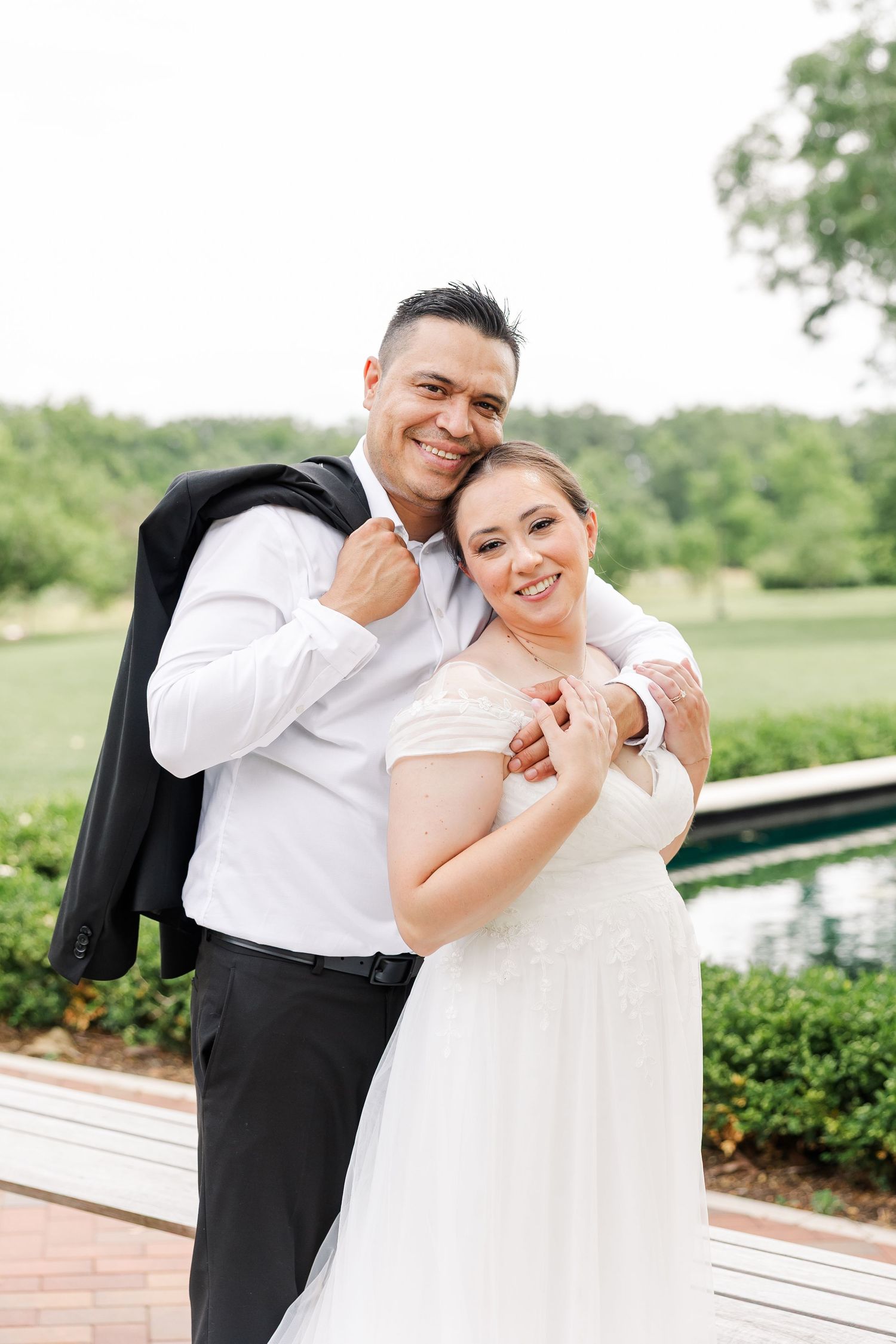 Monika and Rafael smiling together as he carries his suit jacket over his shoulder.