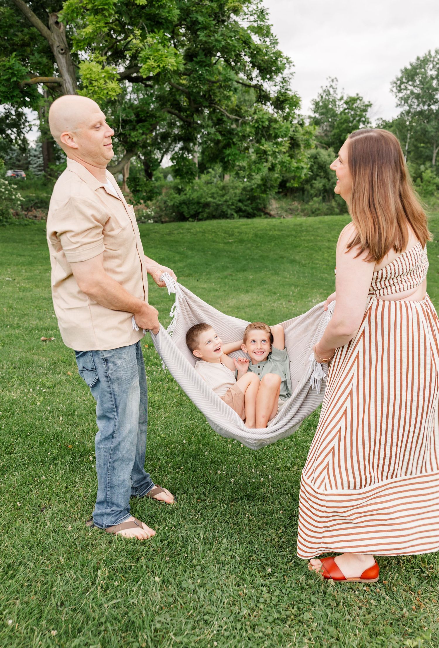 Parents swinging their son in a blanket during a playful family session at Shamrock Hills Park.