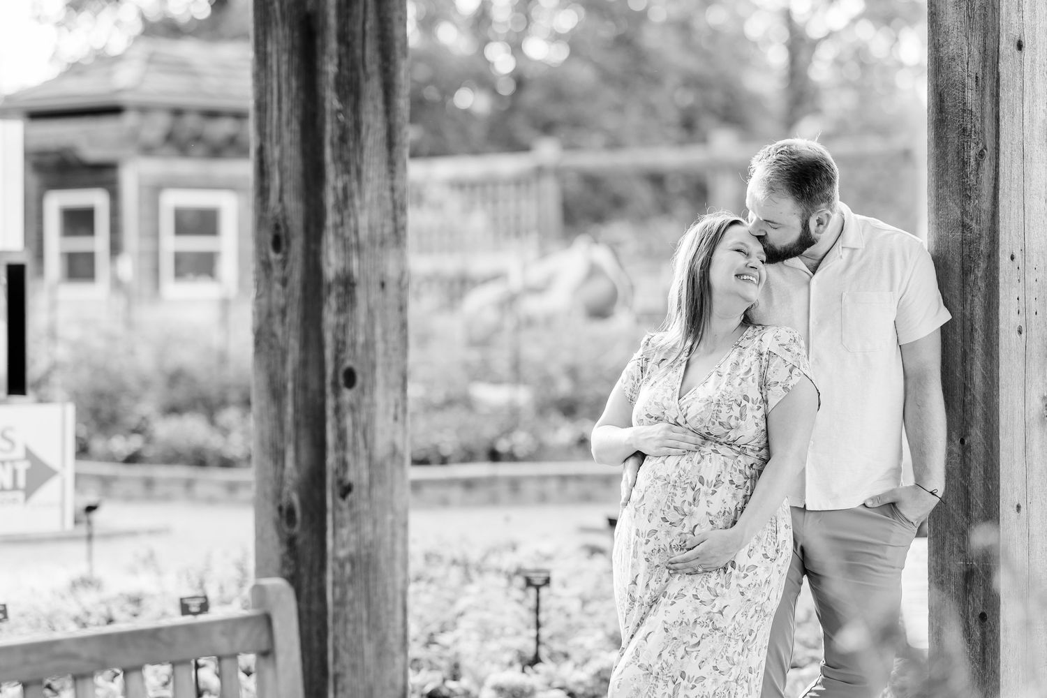 Black and white maternity photo of expecting parents cuddling under a garden pergola at Cantigny Park