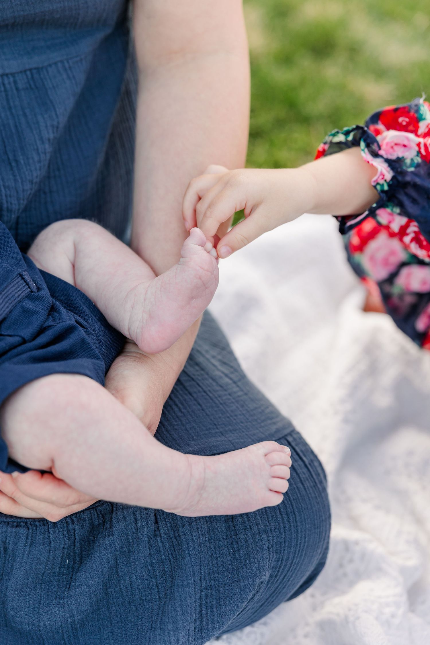 Close-up of Caroline gently holding newborn Lincoln’s toes during their outdoor family portraits.