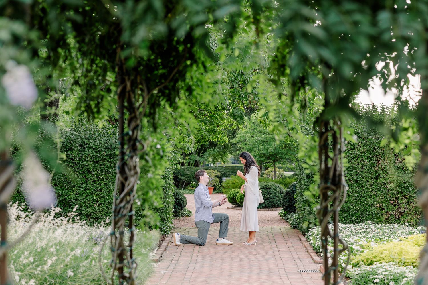 Alysia covers her face in surprise as Jack holds out the engagement ring.